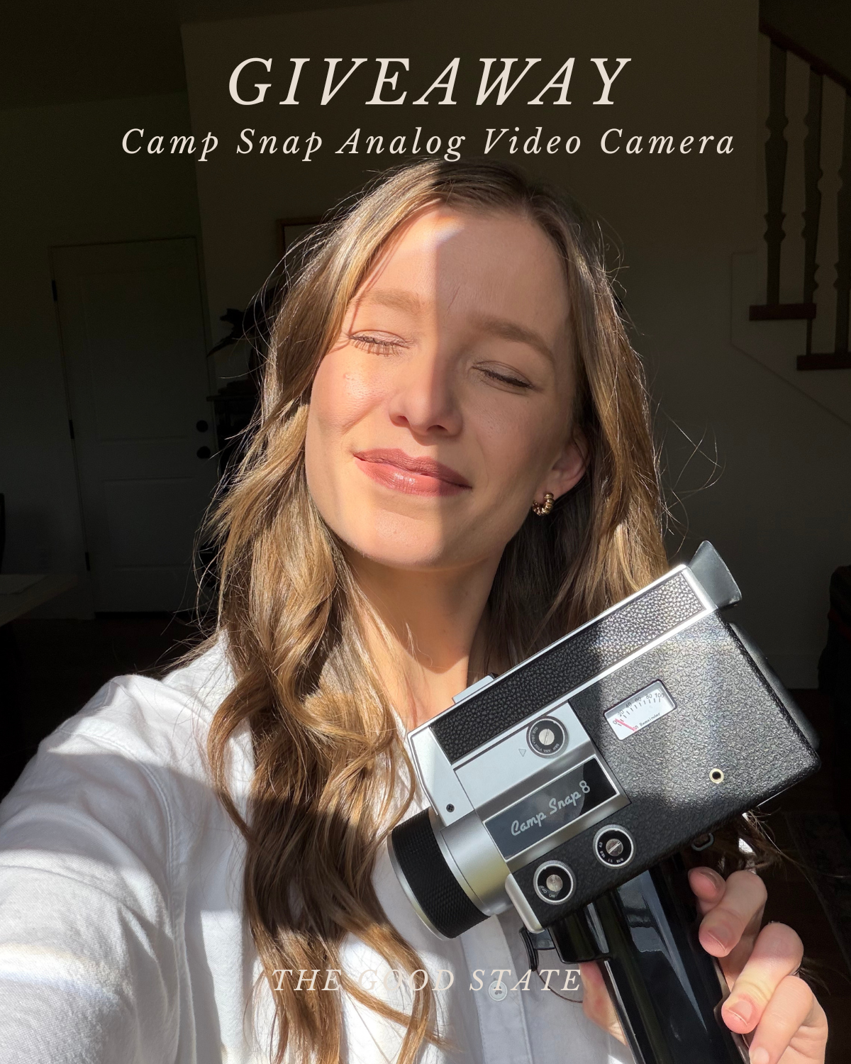 A woman with long wavy hair holding a vintage camera, head slightly tilted, sunlit face, wearing a white shirt, inside a home, stairs in background, text overlay advertising a camera giveaway.