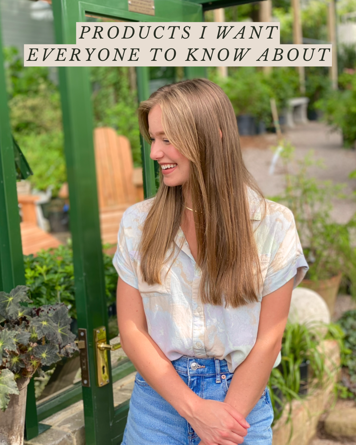 A young woman with long brown hair smiling in a garden center, standing by a green door with a sign that reads 'Products I Want Everyone to Know About'.