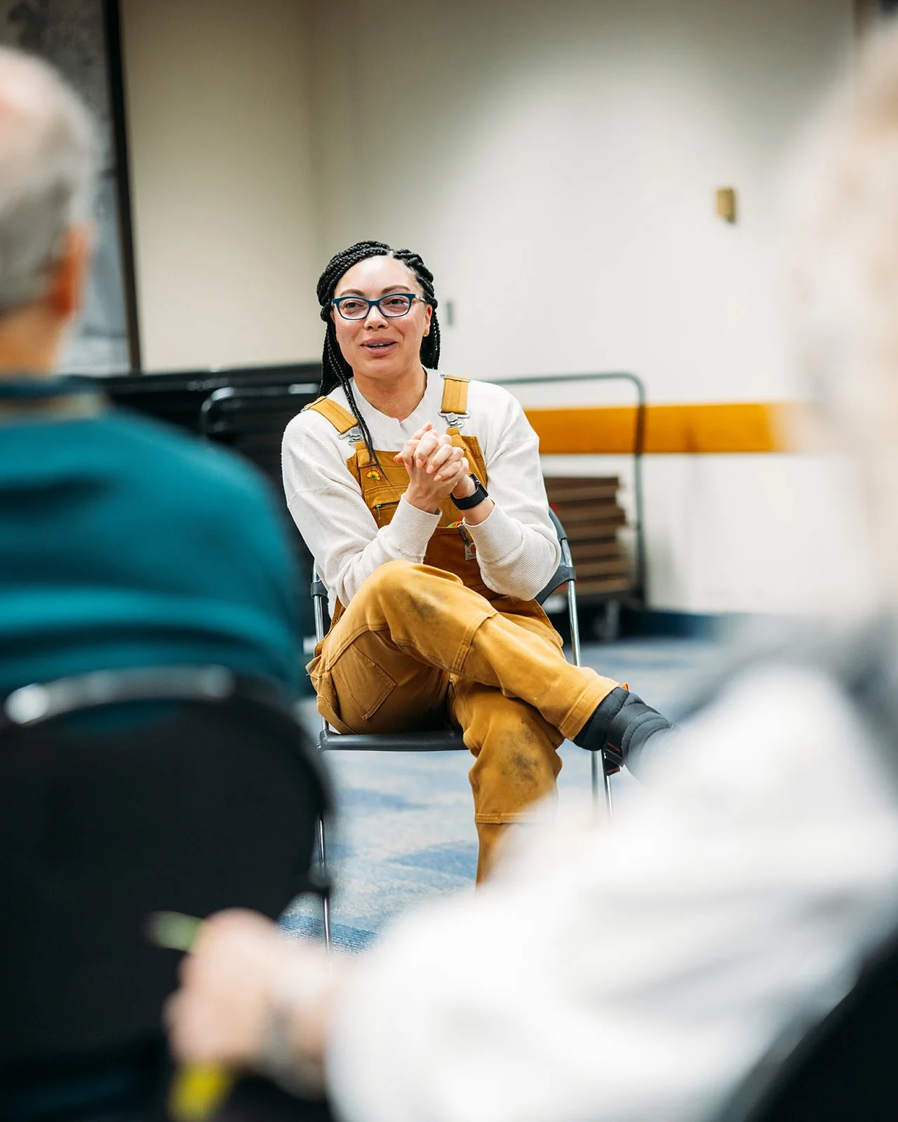 Image of Löki wearing brown overalls, white sweater, and with her hair in box braids