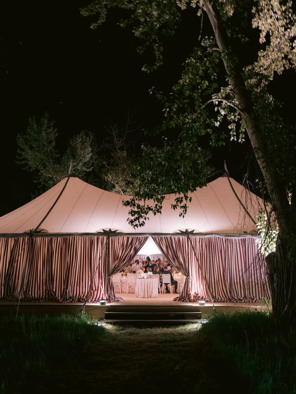 laurie-arons-special-events-montana-family-estate-wedding-striped-tent-at-night-glowing-tented-wedding-reception-private-ranch-montana.jpg