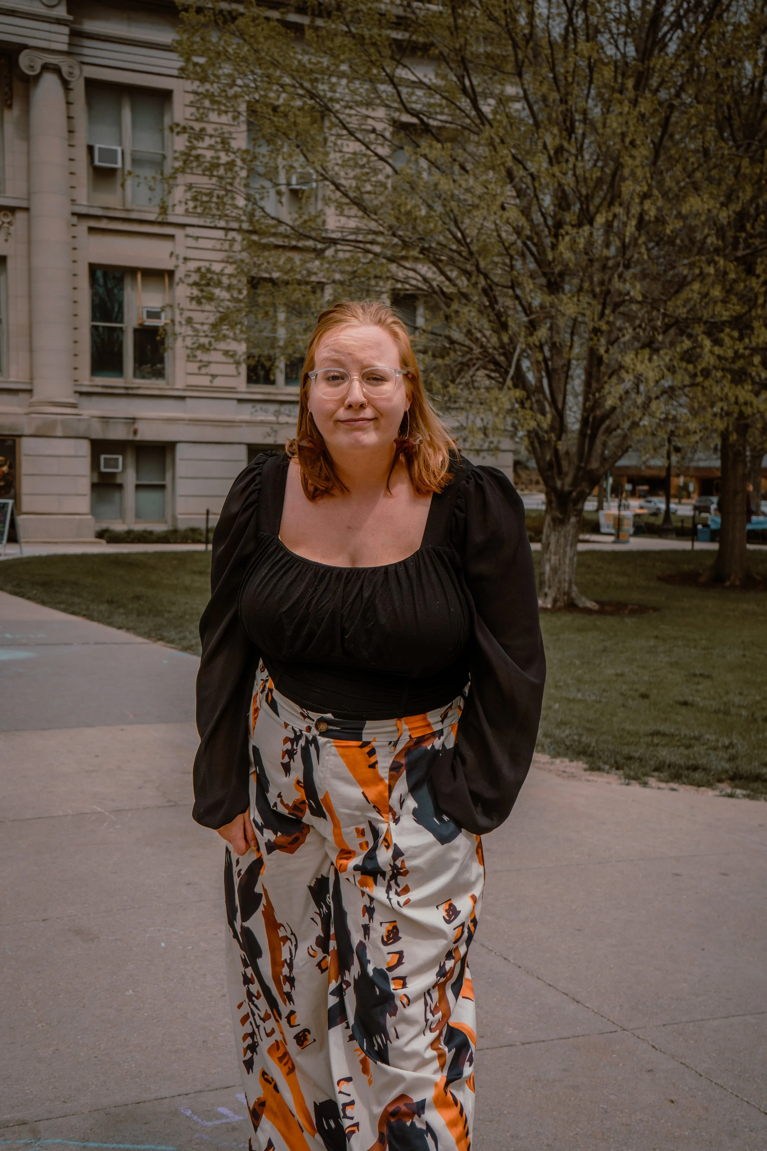 A WOMEN STANDING OUTSIDE OF THE UNIVERSITY IOWA OLD CAPITAL BUILDING FOR GRADUATION PHOTOS