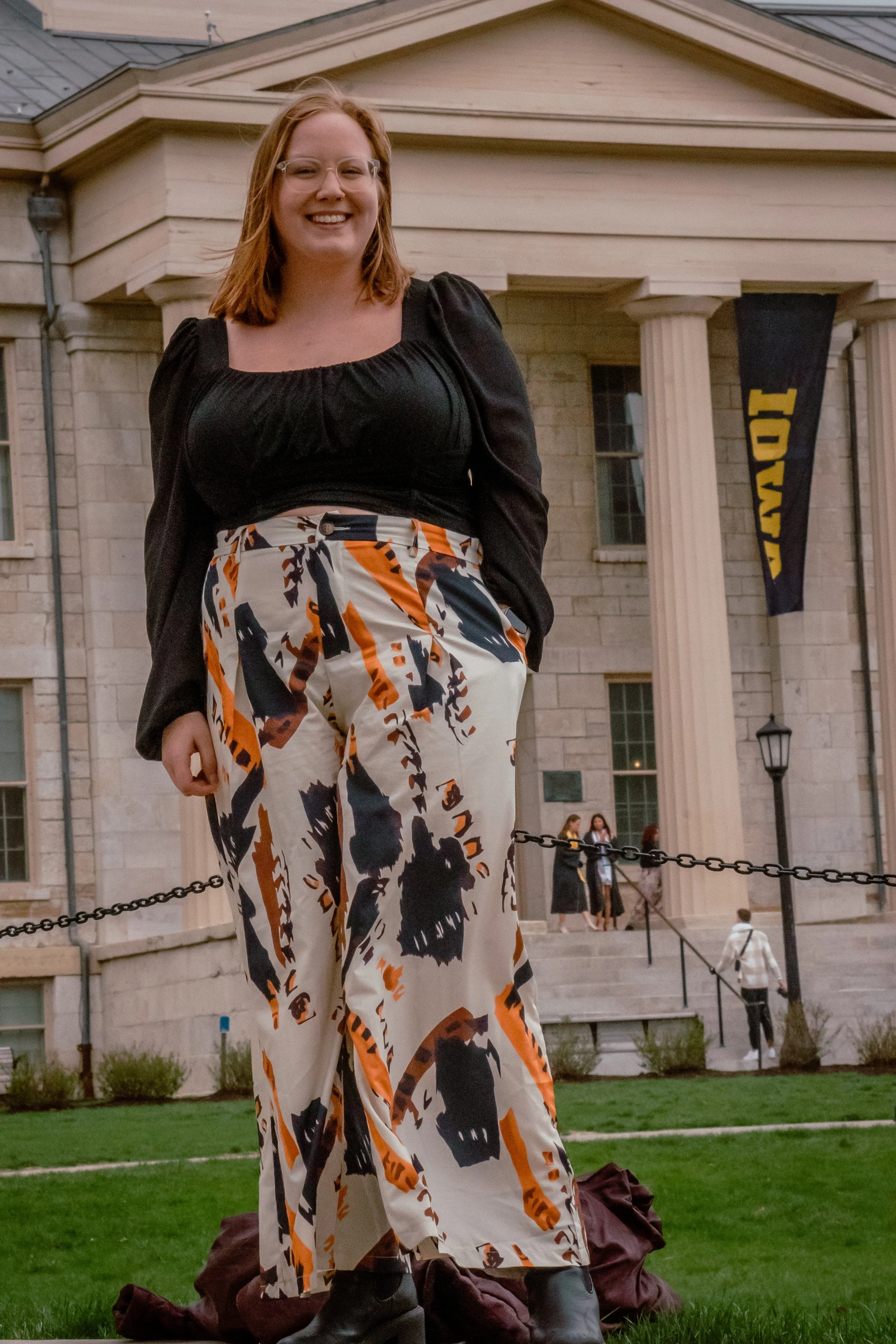 A WOMEN STANDING OUTSIDE OF THE UNIVERSITY IOWA OLD CAPITAL BUILDING FOR GRADUATION PHOTOS