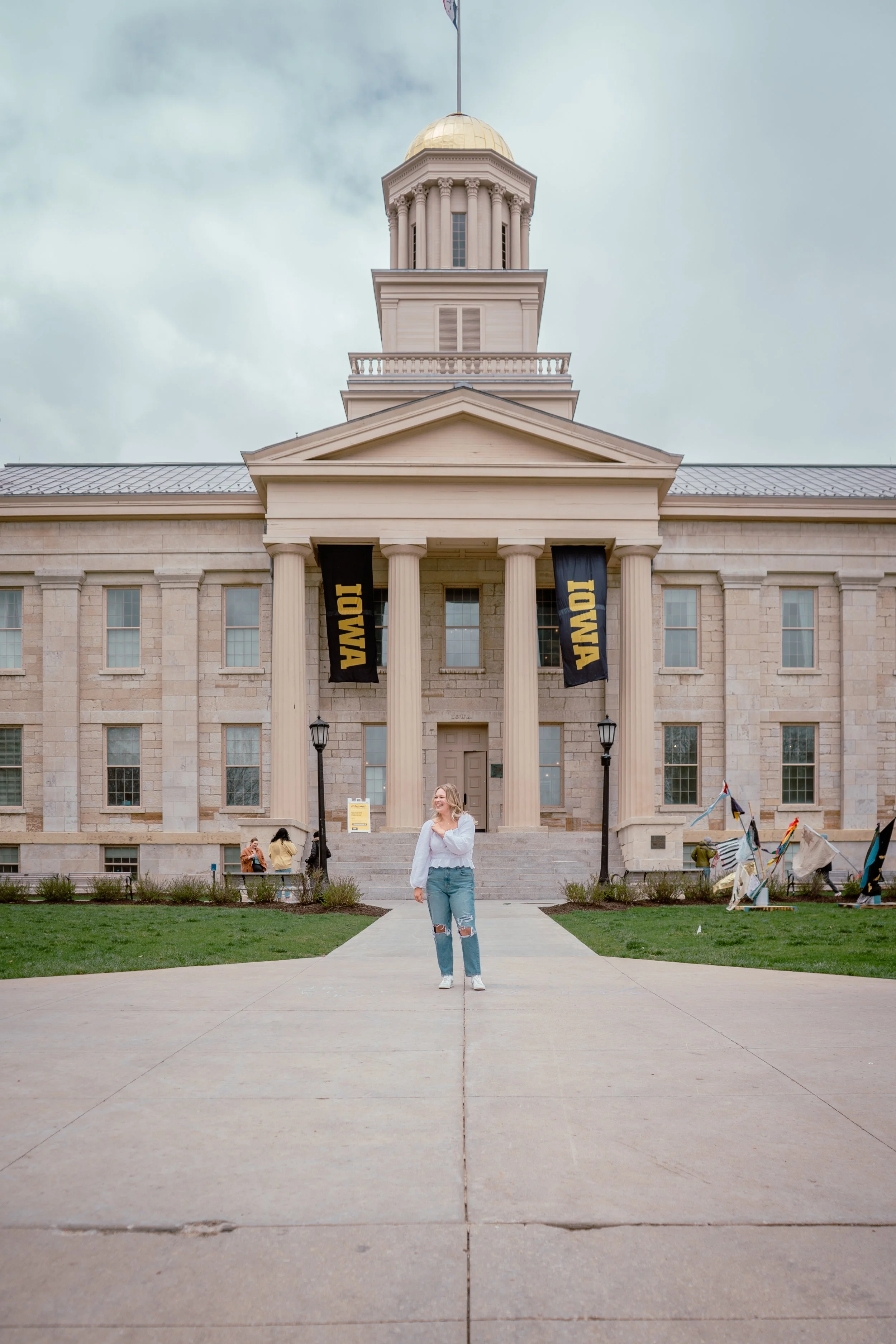 A WOMEN IN FROM OF THE OLD CAP IN IOWA CITY IOWA FOR GRADUATION PHOTOS