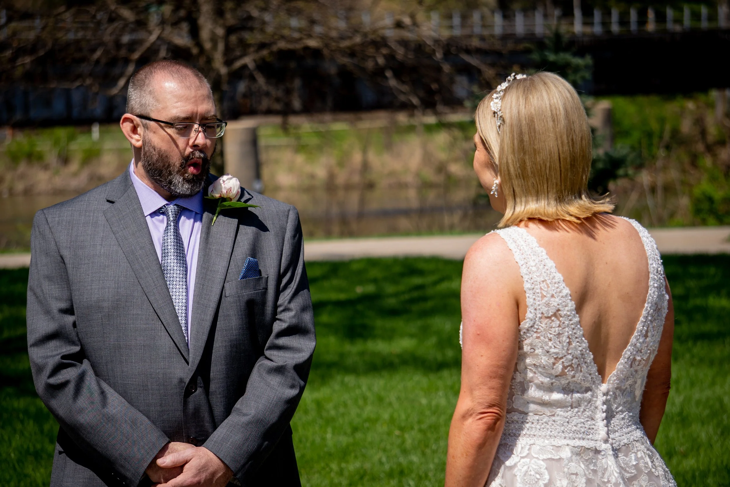 A BRIND AND GROOM PICTURED IN THE FIRST LOOK IN THE WEDDING DRESS, THE GROOM HAS A LOOK OF ABSOLUTE ASTONISHMENT 