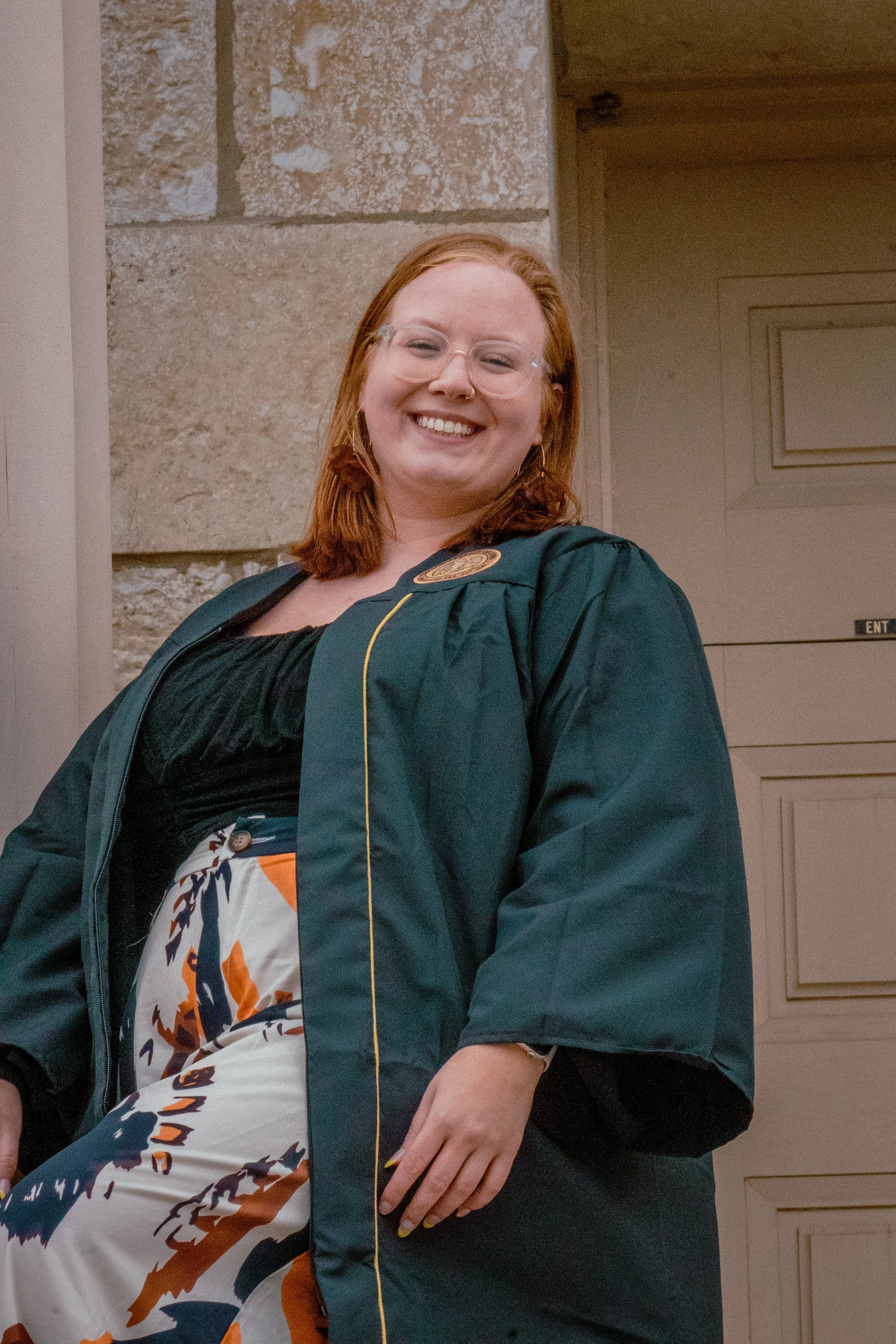 A WOMEN STANDING OUTSIDE OF THE UNIVERSITY IOWA OLD CAPITAL BUILDING FOR GRADUATION PHOTOS