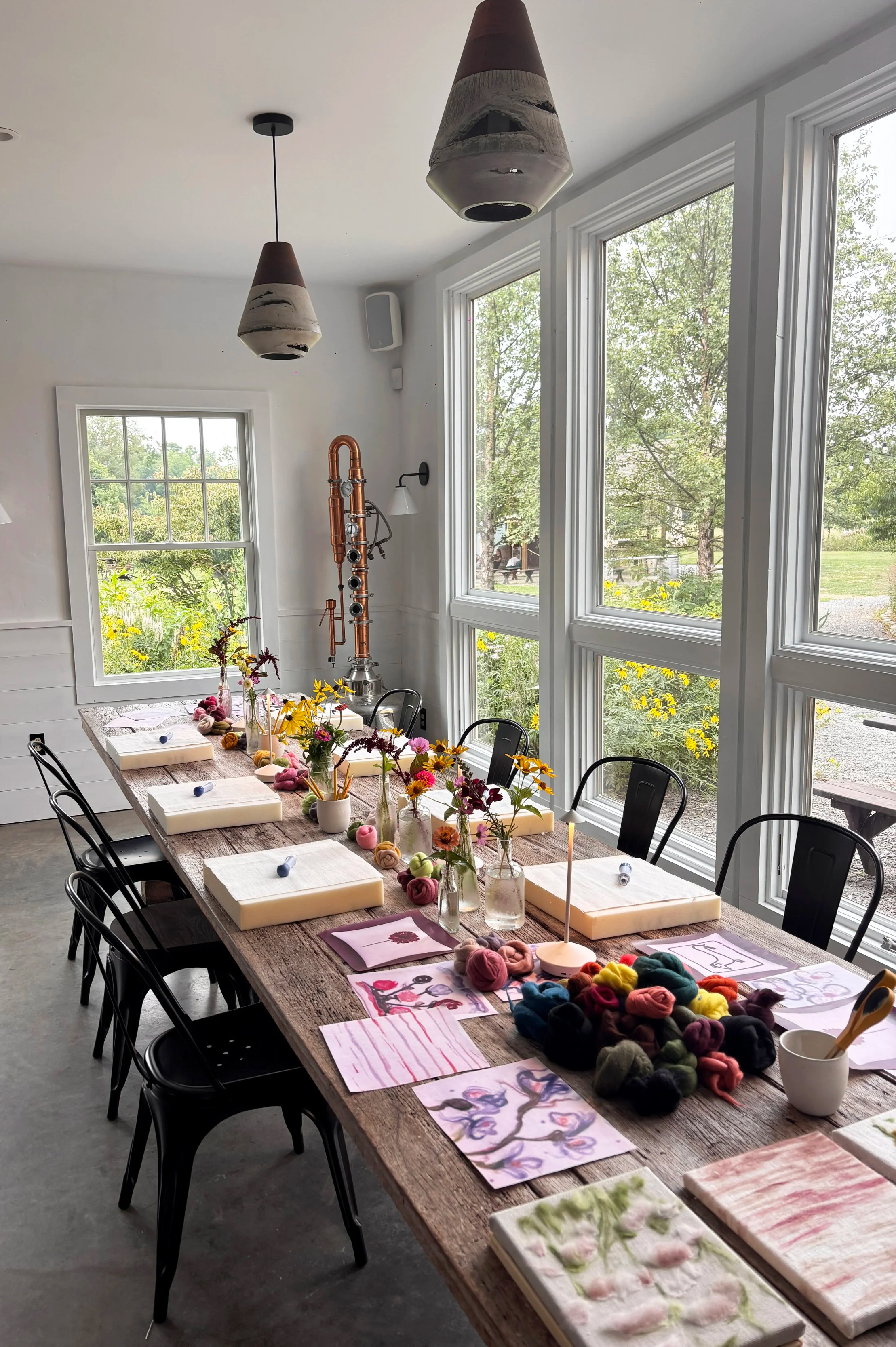 Bright studio space set up for a Paint with Wool workshop, Le Studio Anthost, New York, with wool, drawings, and table settings.