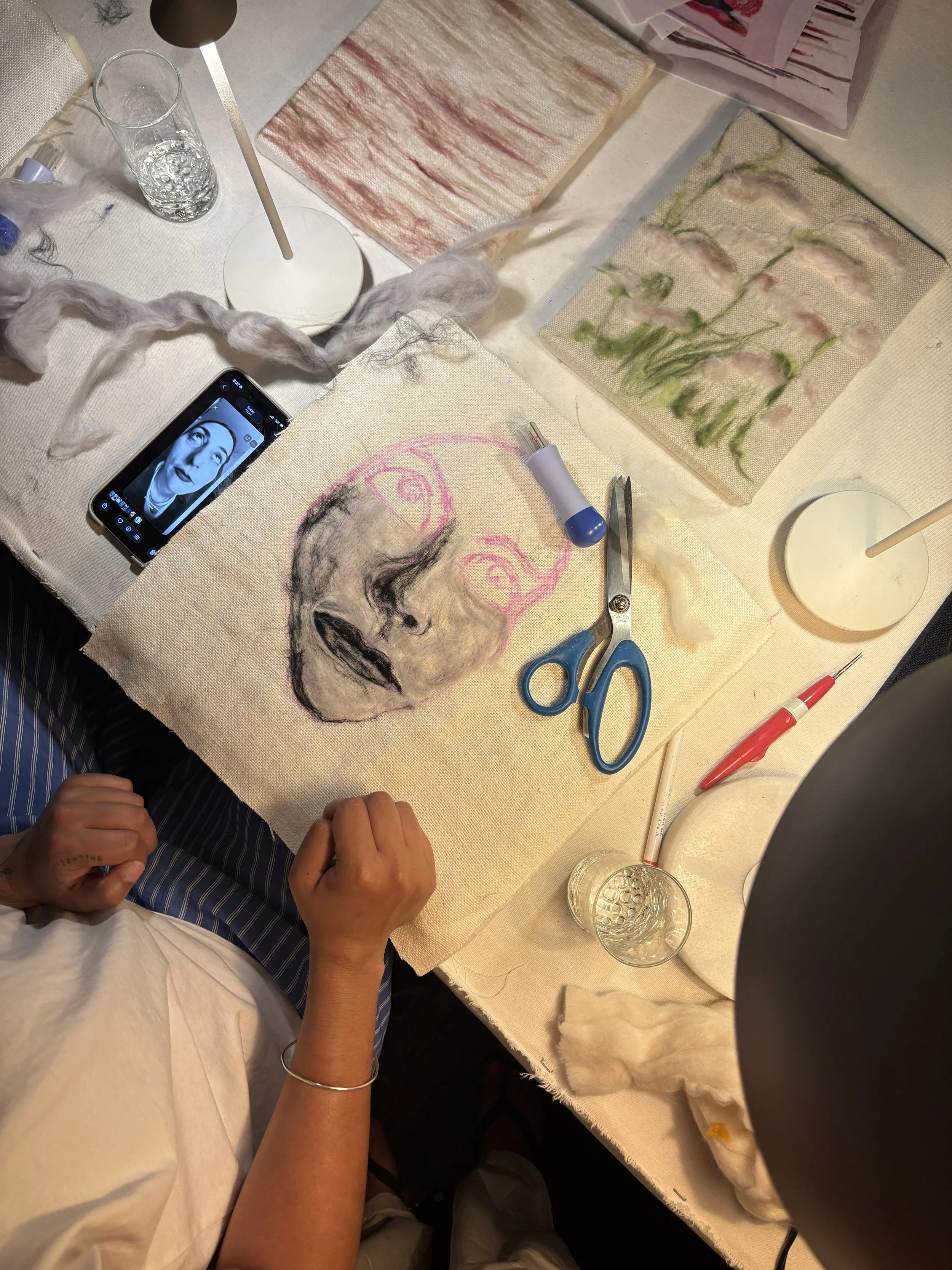 Guest working on a Paint with Wool piece, Le Studio Anthost, New York, with fabric sketches, wool, and craft tools on the table.