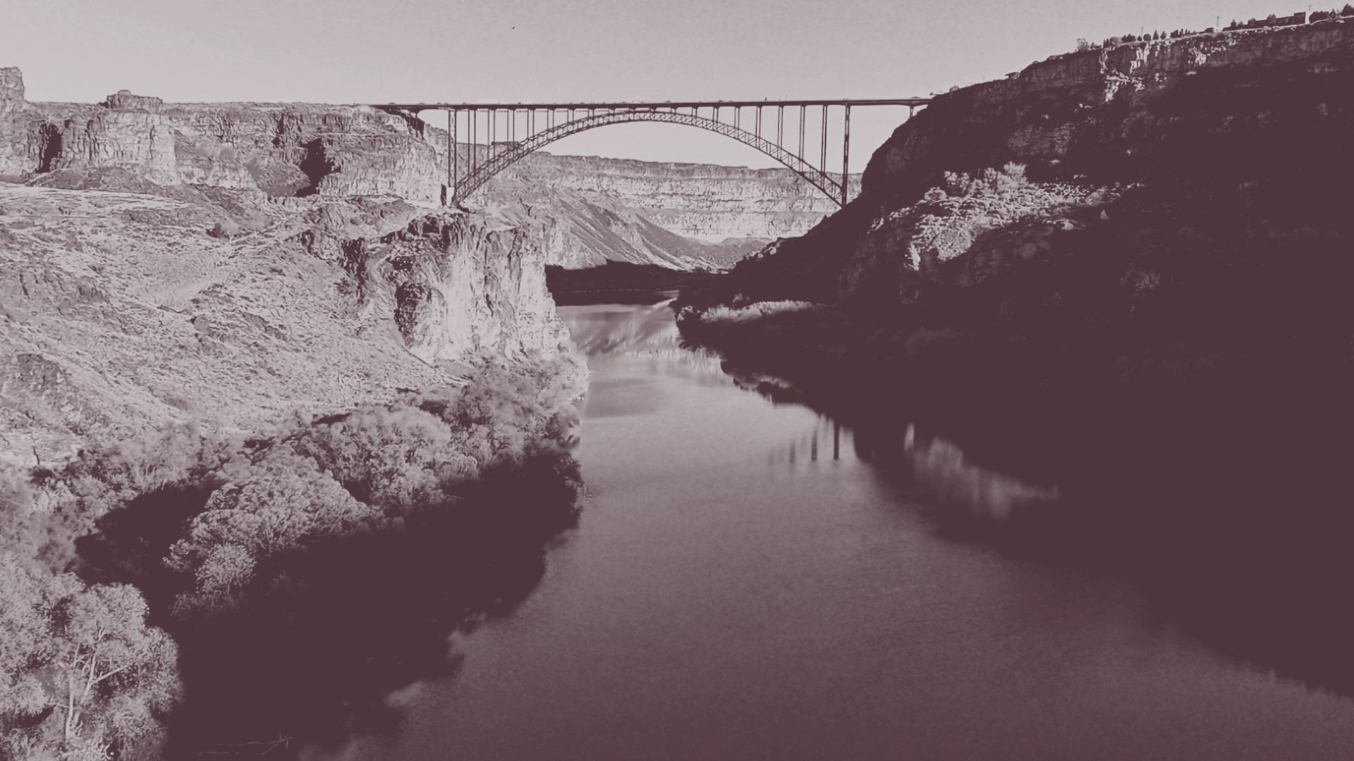 Steel arch bridge crossing a canyon with river below and rocky cliffs on both sides