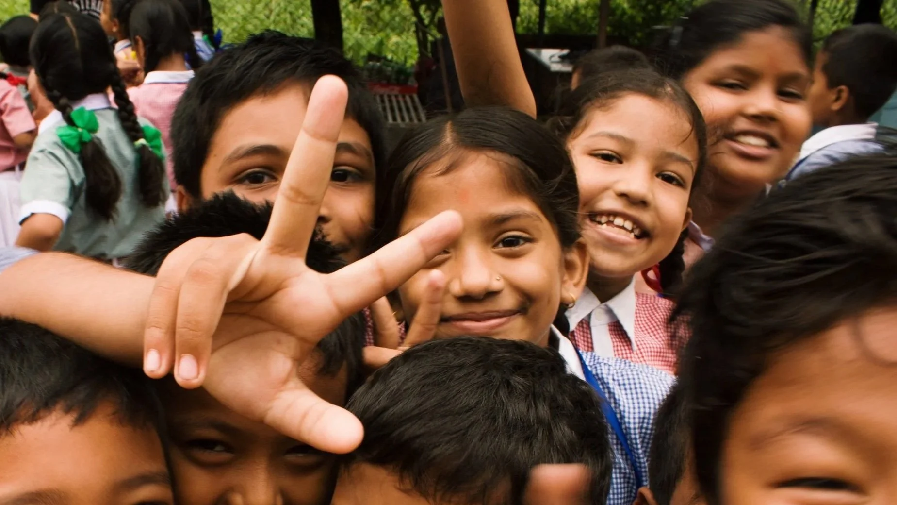 Group of smiling children making peace signs and gestures