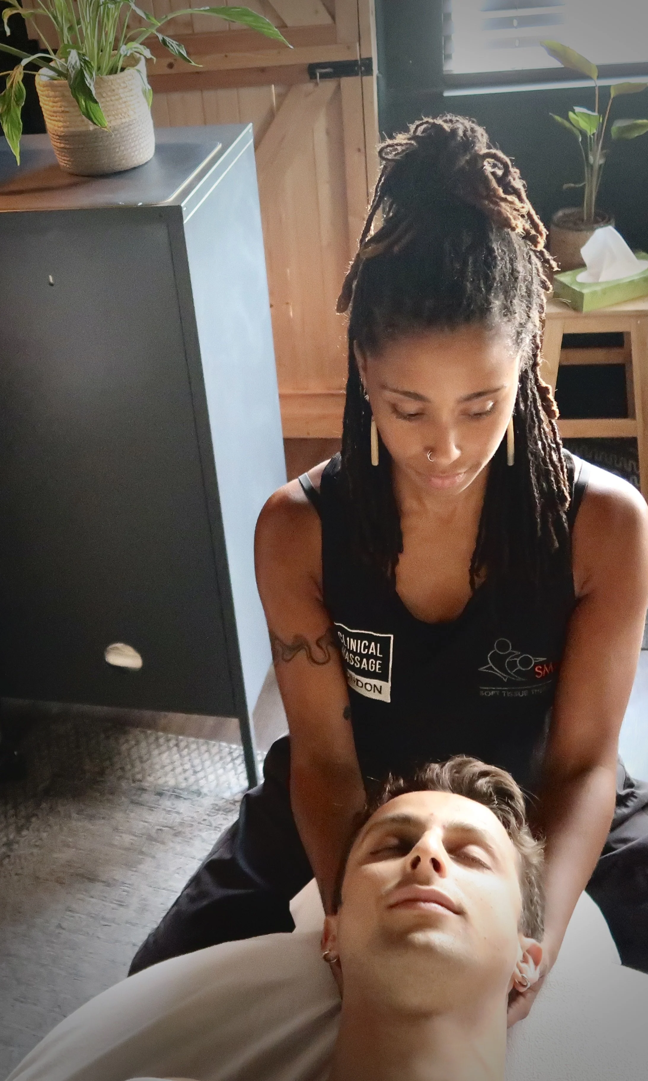 Massage therapist Channara working on the deep neck extensor muscles to provide relief from chronic tension that can lead to headaches at our clinic in Dalston.