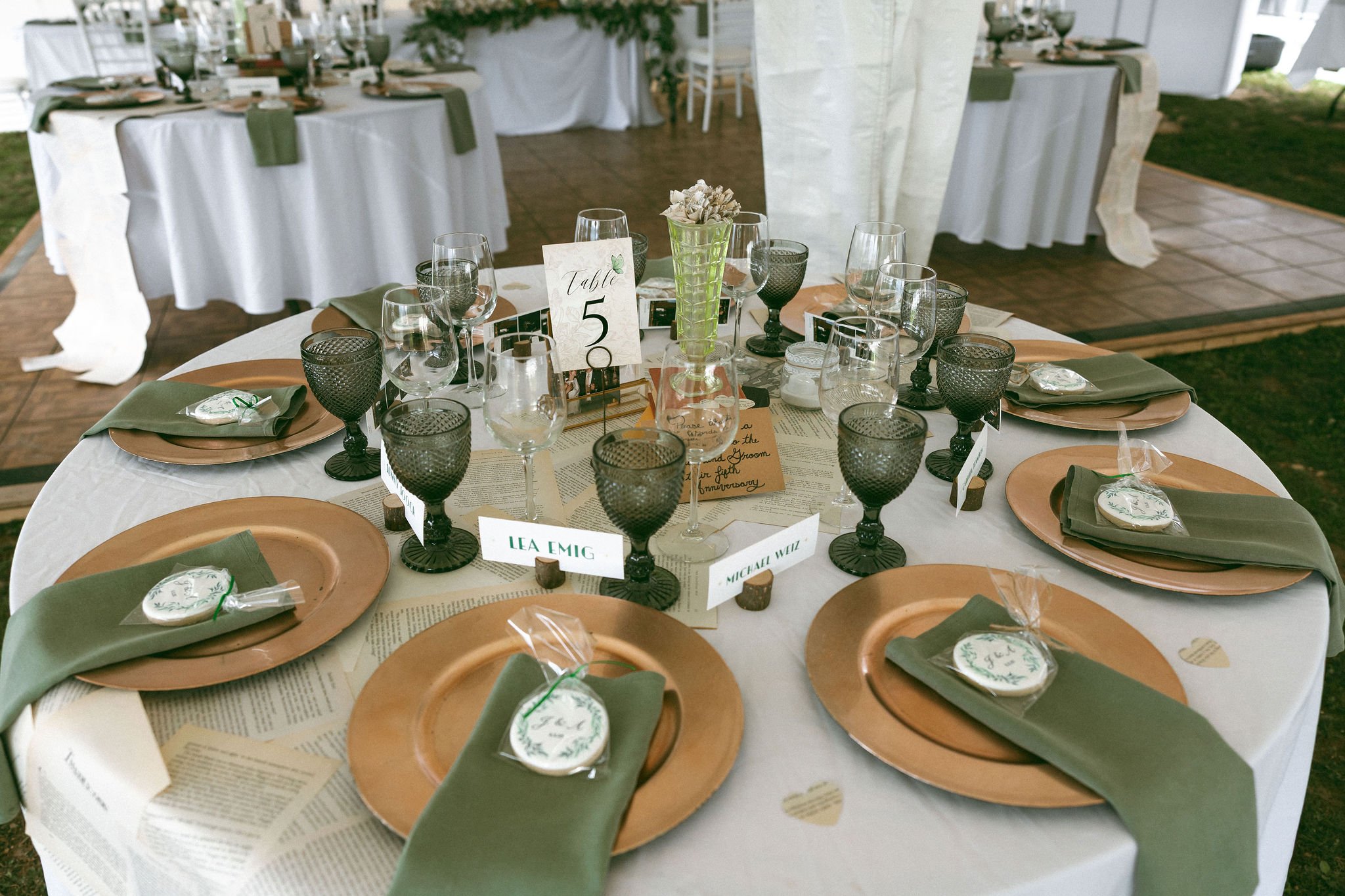 Green and fold reception table setting for a tented wedding with book-page runner