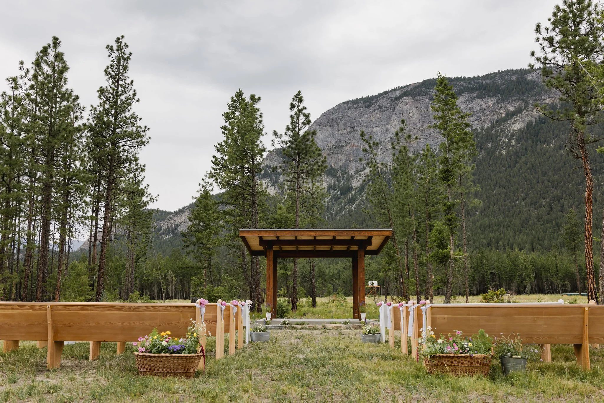 Ceremony arbor framed by wooden benches and mountain backdrop at a Western Chic BC wedding.