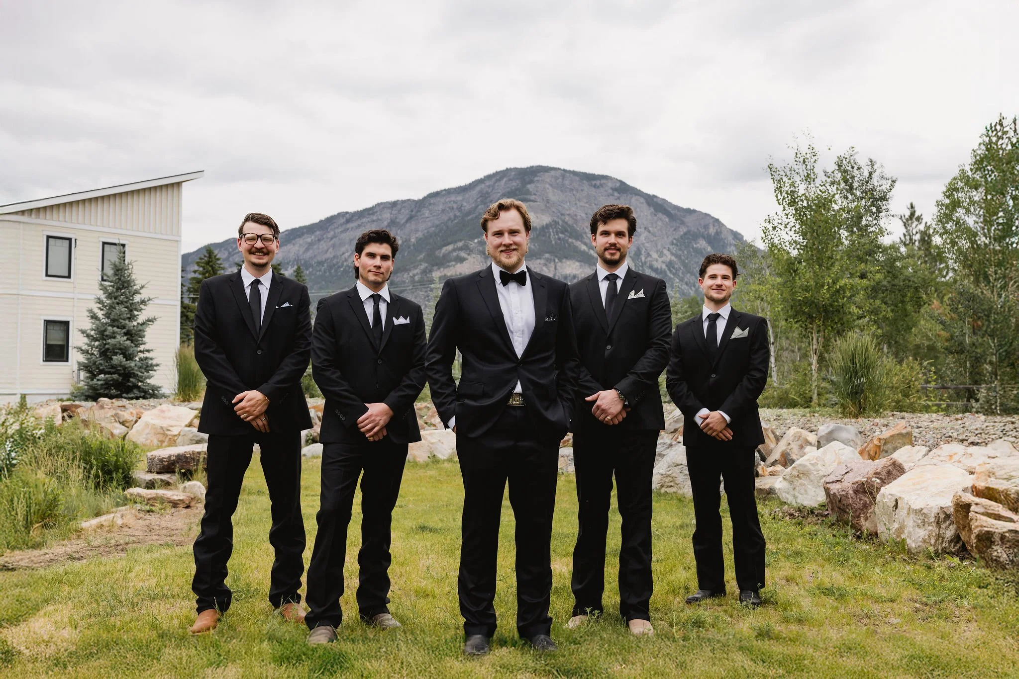 Groom with groomsmen in black suits at Western chic BC wedding in British Columbia mountains.
