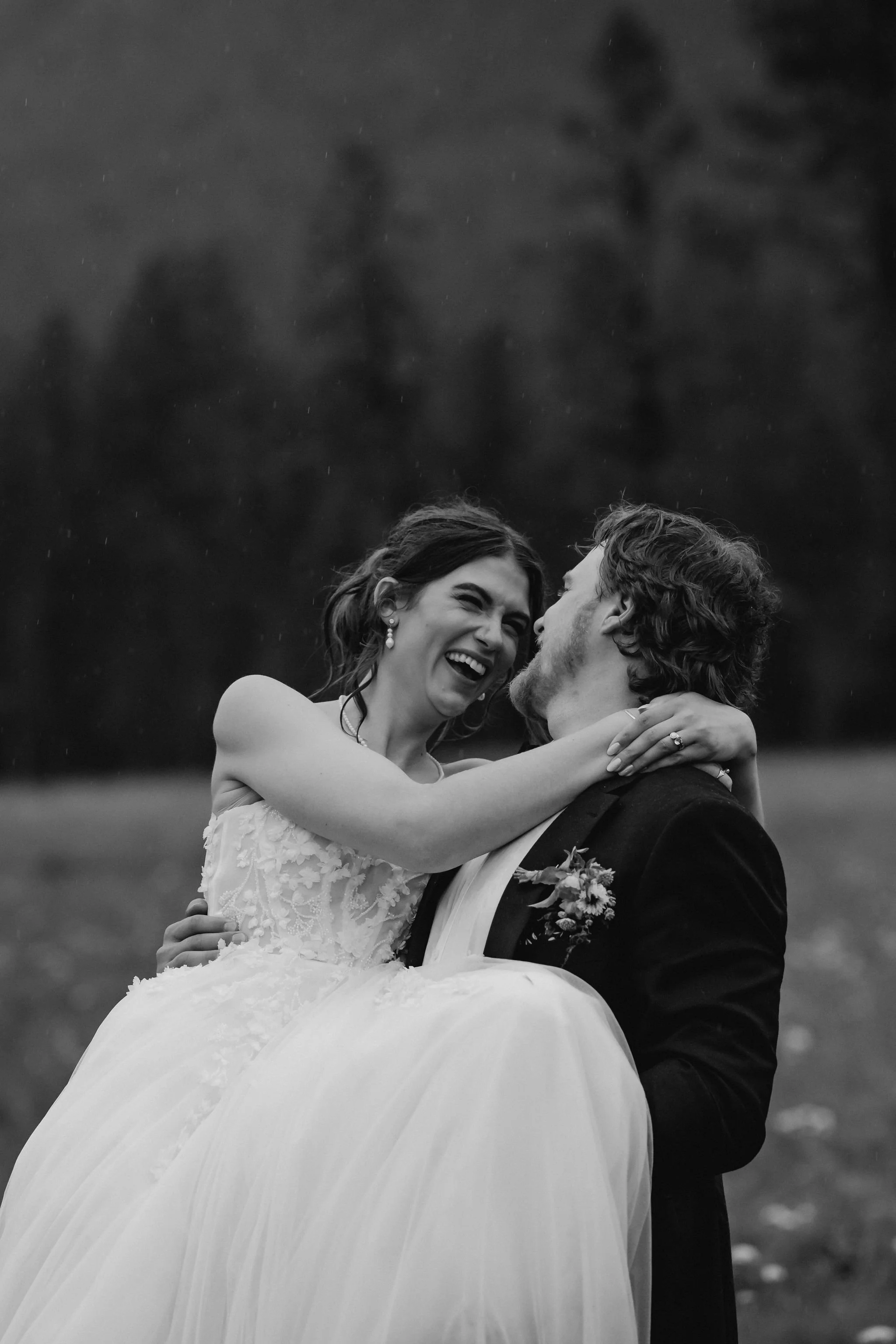 Groom carrying his bride as they laugh in the rain at a Western chic BC wedding.