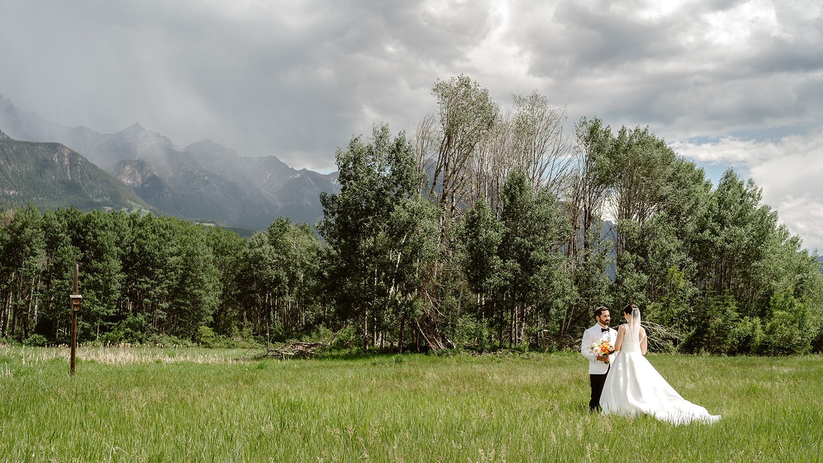 The bride and groom share a quiet moment during their romantic mountain wedding, set against a breathtaking mountain backdrop