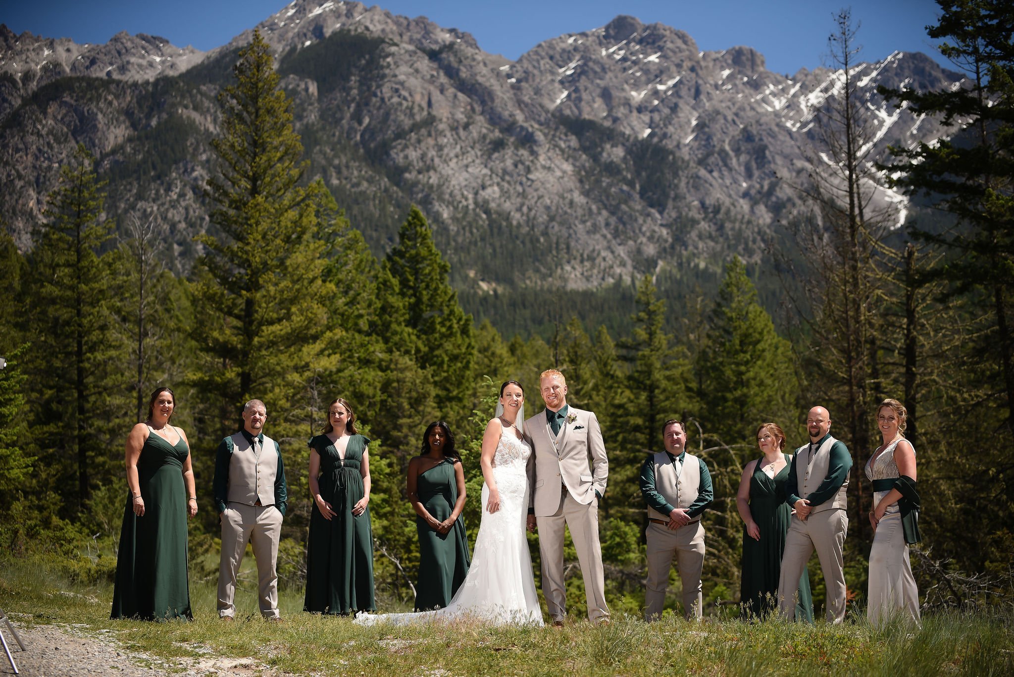 Wedding party group protrait with the group standing slightly apart in front of the mountains during a ski resort wedding