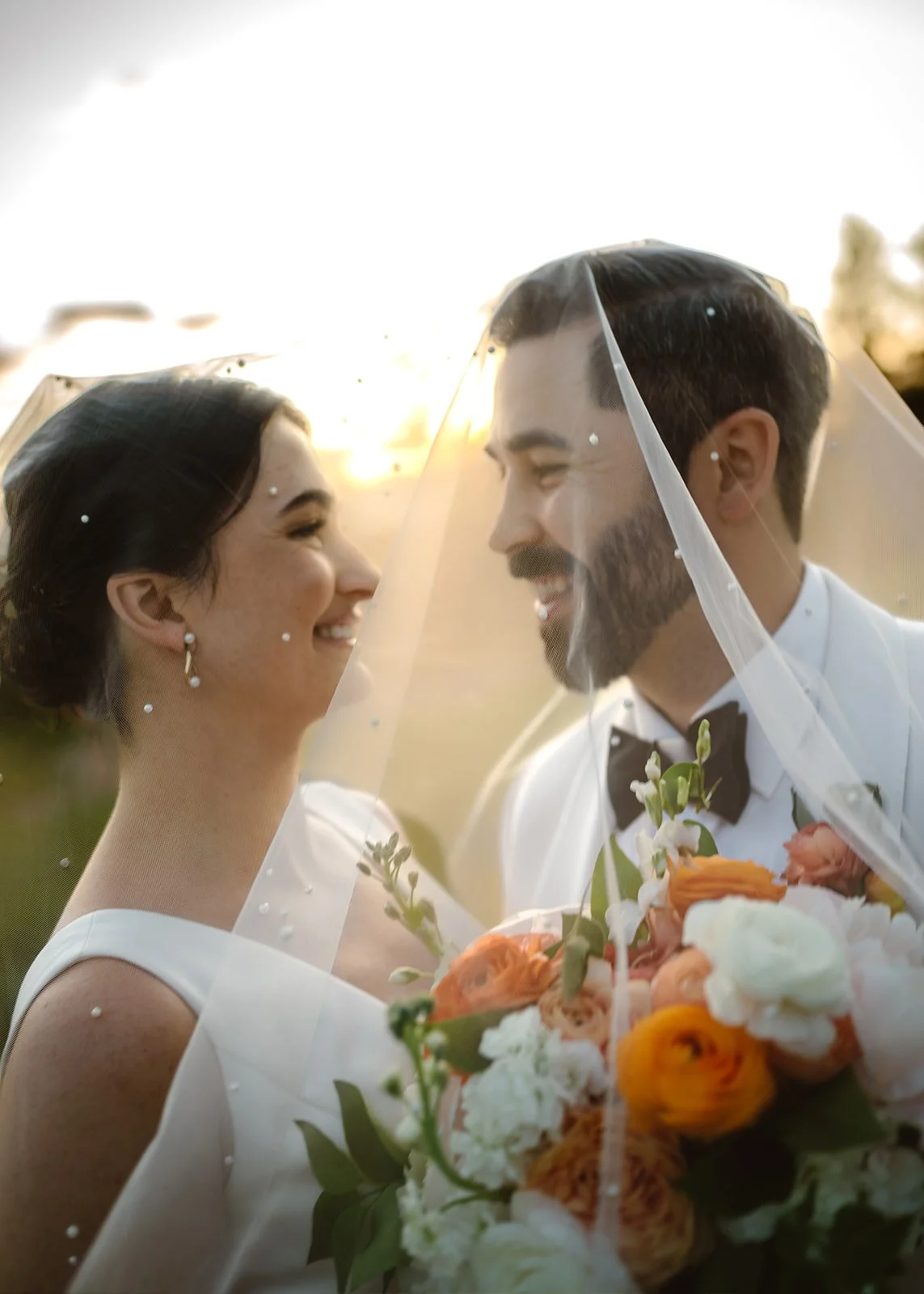 The bride and groom stare into each other's eyes under the bride's veil during their romantic mountain wedding