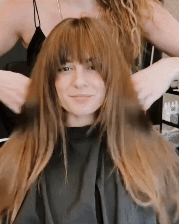 Woman with long, straight, light brown hair having her hair styled by a hairstylist.