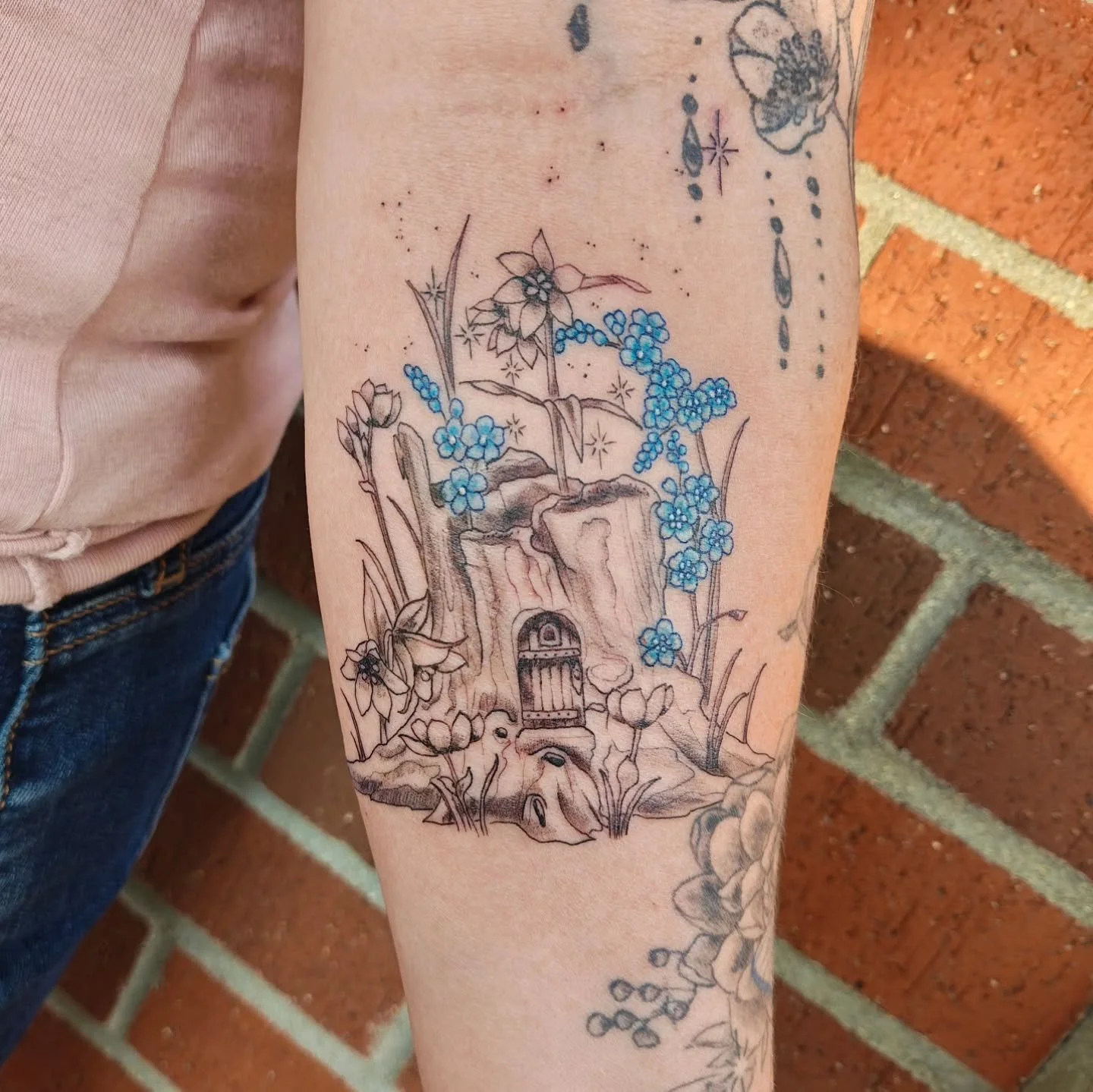 Fairy tree stump for Kat! This is such a favorite, I love the pop of blue in the forget me nots! They are all Alaska wildflowers! โ๏ธ 
.
.
.
Made with:
๐Made at the queer, poc, women/womxn, witch-friendly space, @shieldmaidentattoo 
#Tattoo #Tattoos