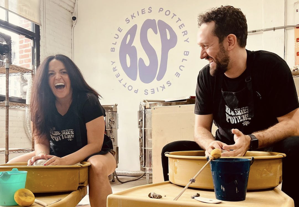 Valerie and Jordan laughing at the wheel, in front of the BSP wall