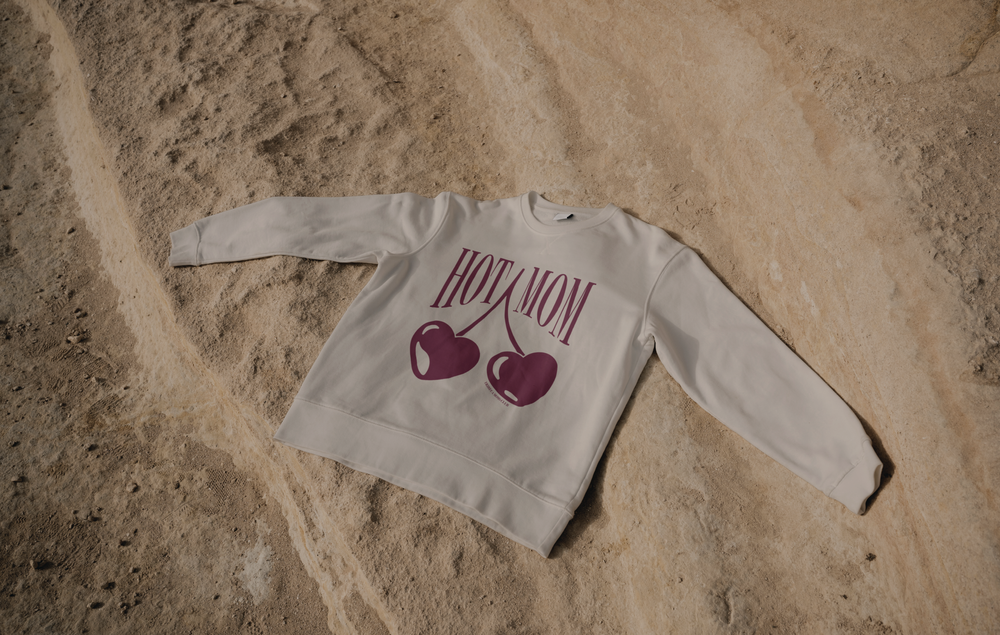The HOT MOM crewneck laid out on sand