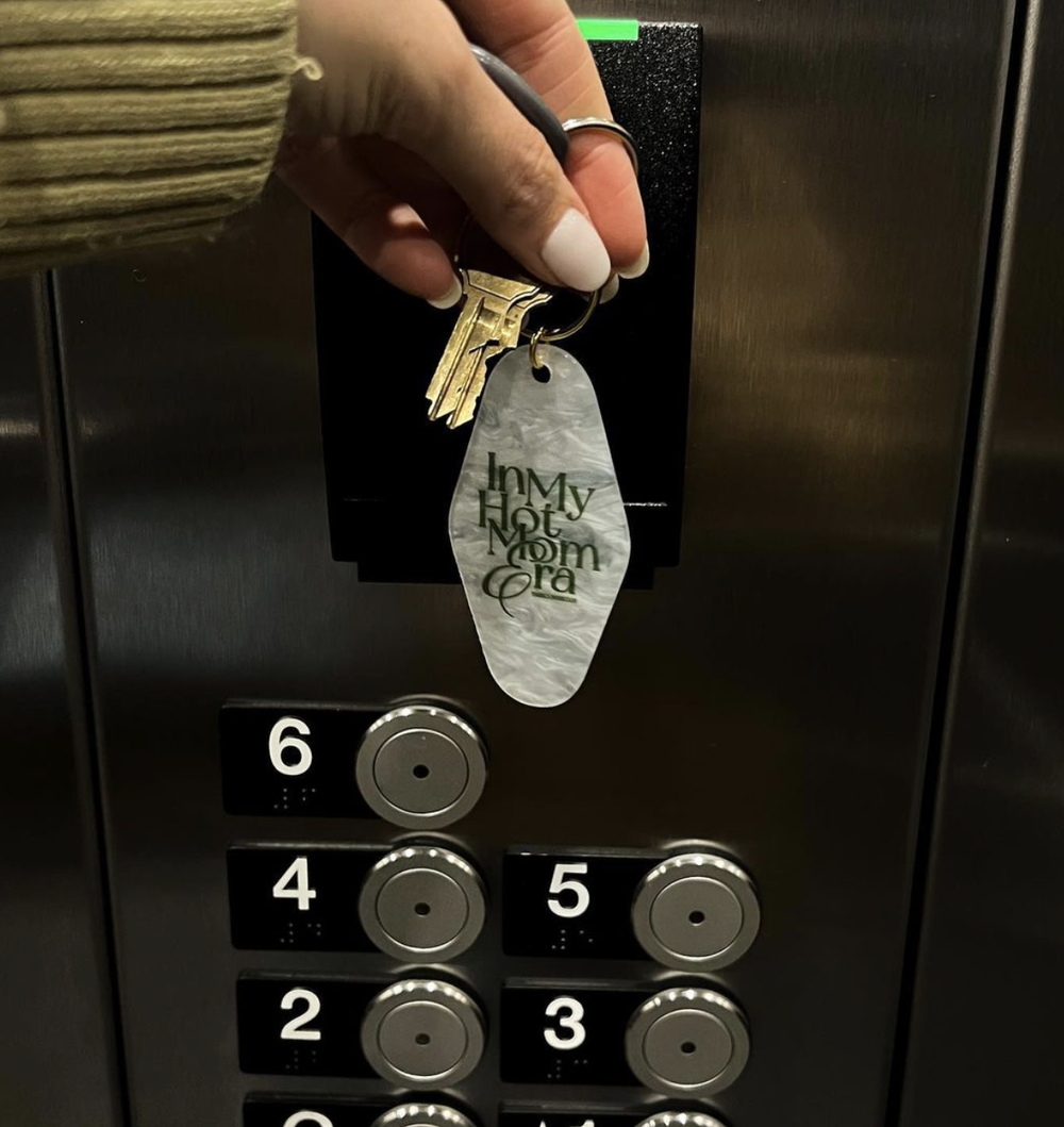 The In My Hot Mom Era motel keychain in an elevator
