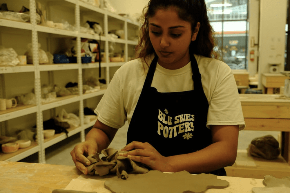 A student hand building in a Blue Skies Pottery apron