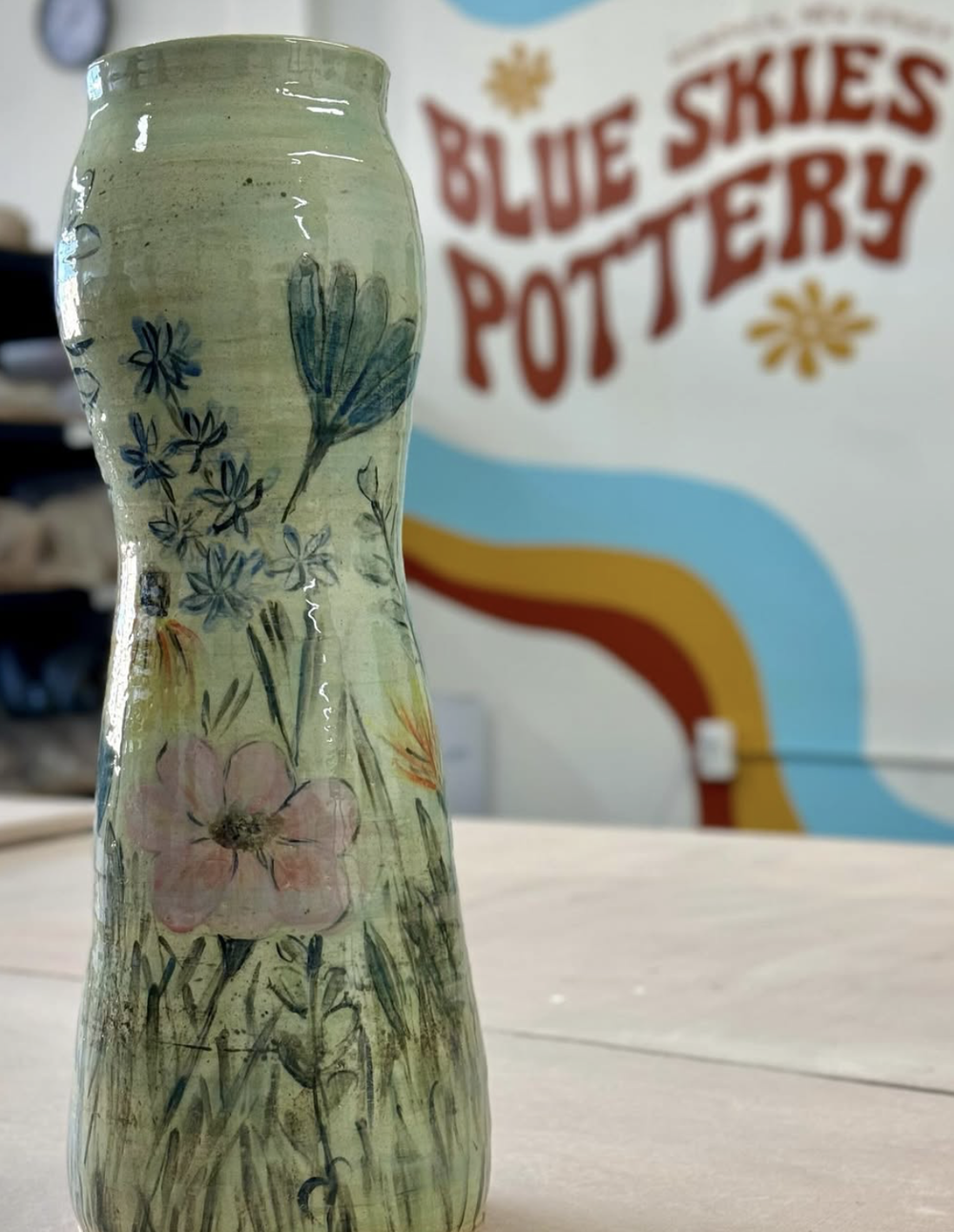 A painted vase in front of the logo wall