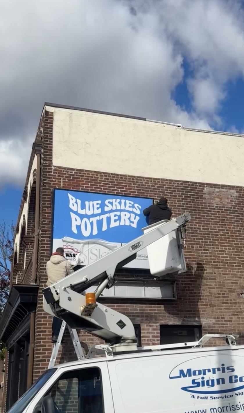 The Blue Skies Pottery sign going up from a bucket truck