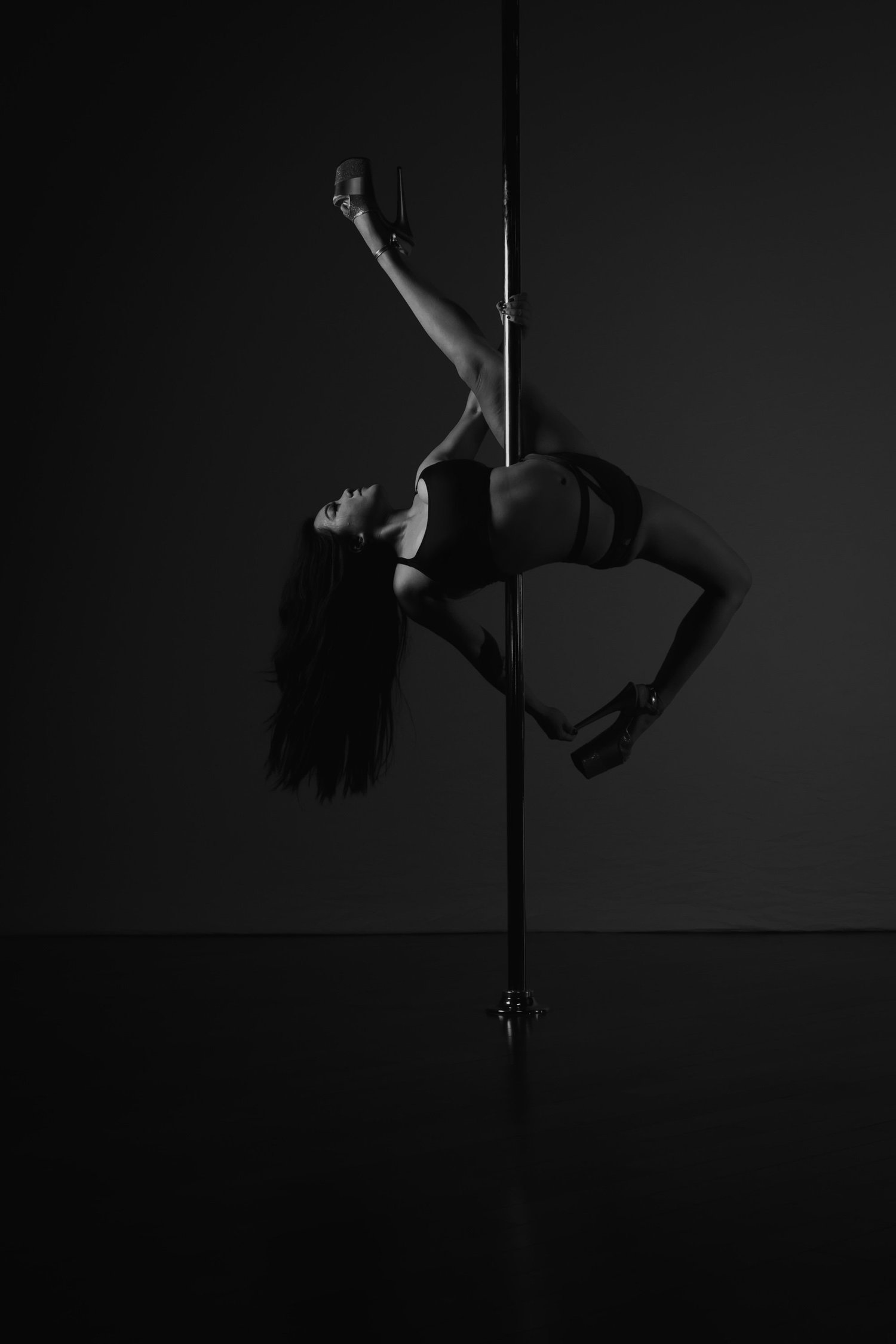 Camille in a back bend on the pole in platform heels, black and white