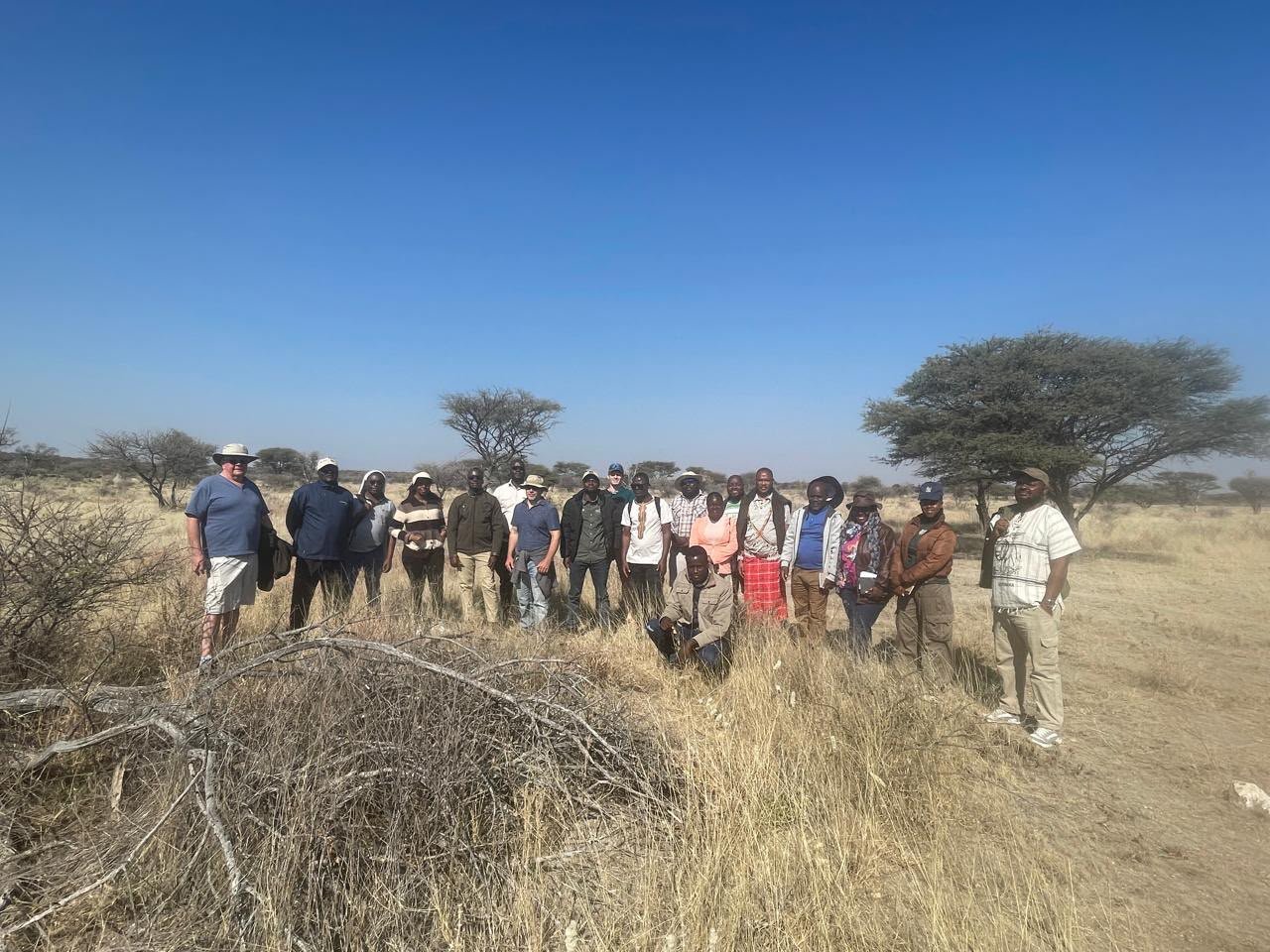 Dr. Brian Child and a cohort of about a dozen certificate program students stand in a savannah area at the field course site in Namibia.