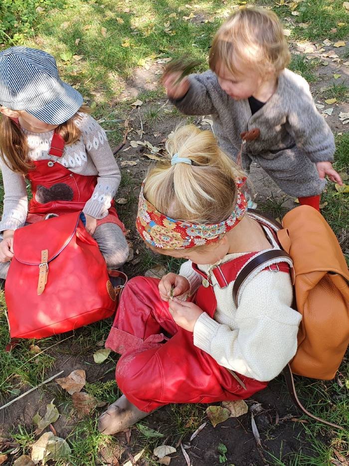 Children are sitting in the woods, eating their lunches
