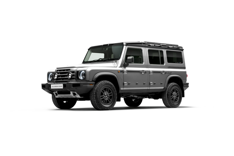 A silver Land Rover Defender parked on a gray surface with a black background.
