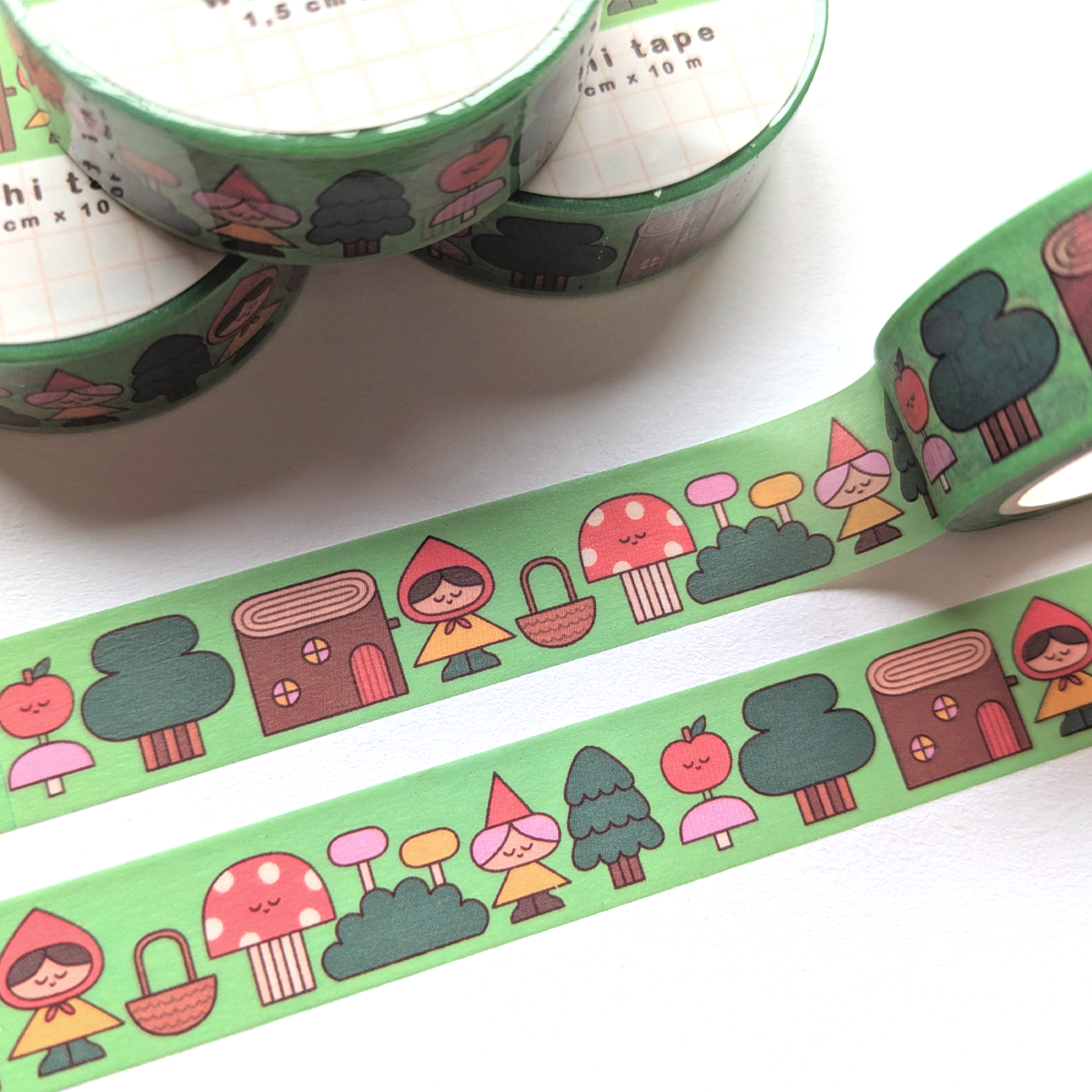 Decorative green washi tape with illustrations of forest elements, including trees, mushrooms, baskets, and characters in yellow and pink outfits.