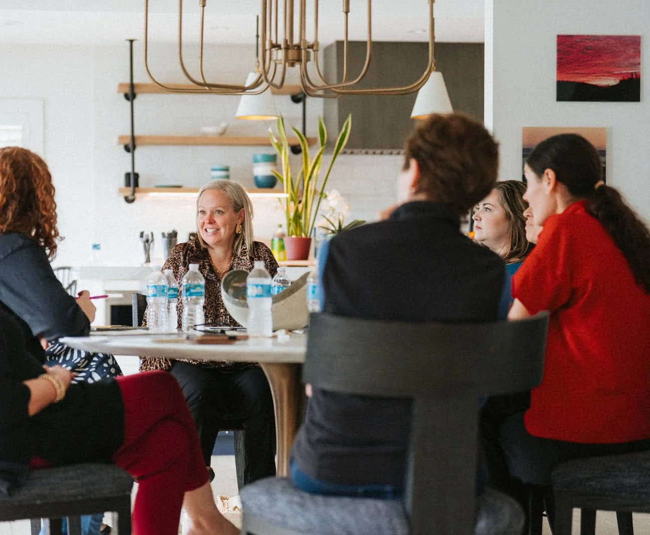 Marti Barrow and PRIDE clients having a healthy discussion about fundraising around a stylish table in an Airbnb