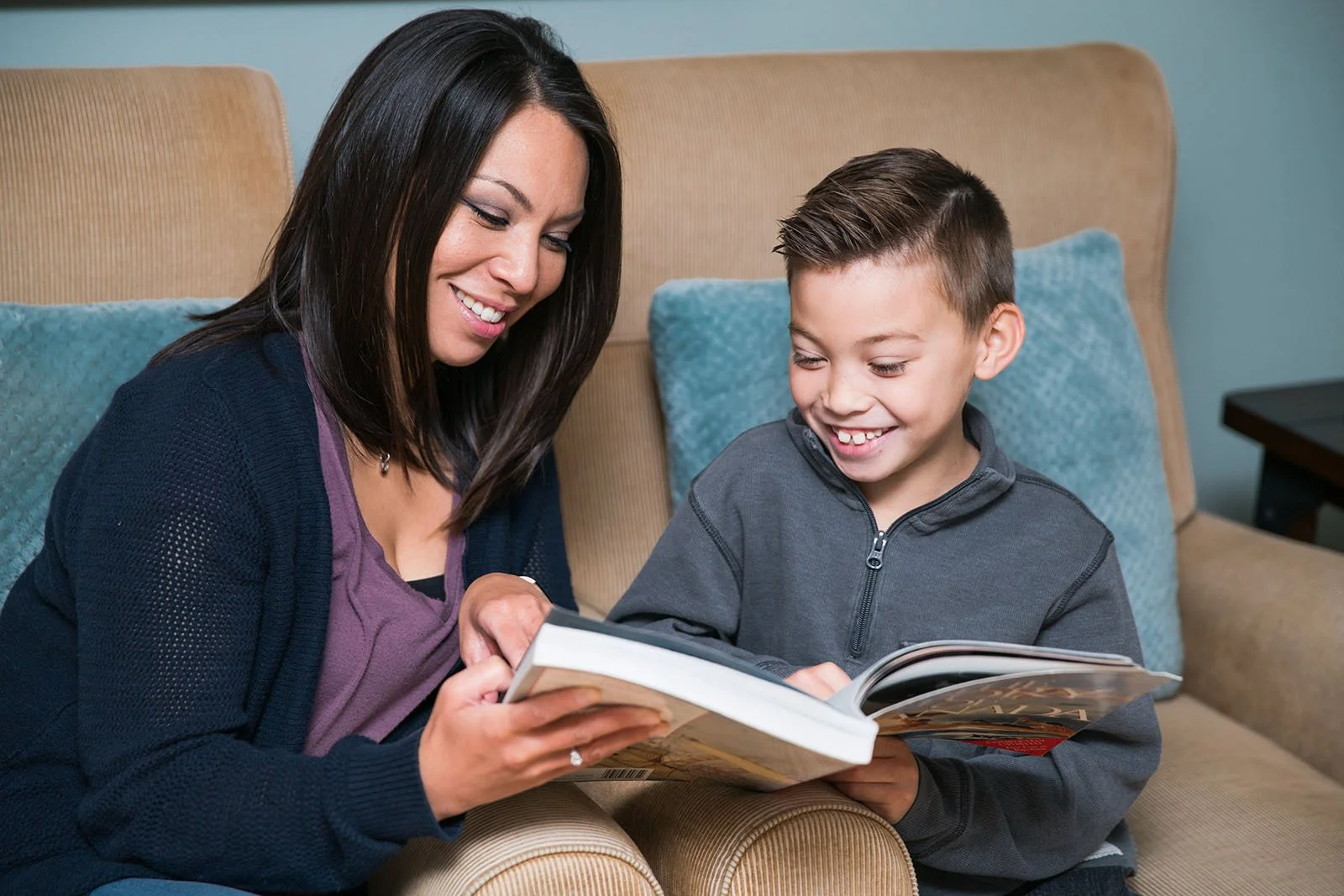 Mother and son reading a book together on the couch