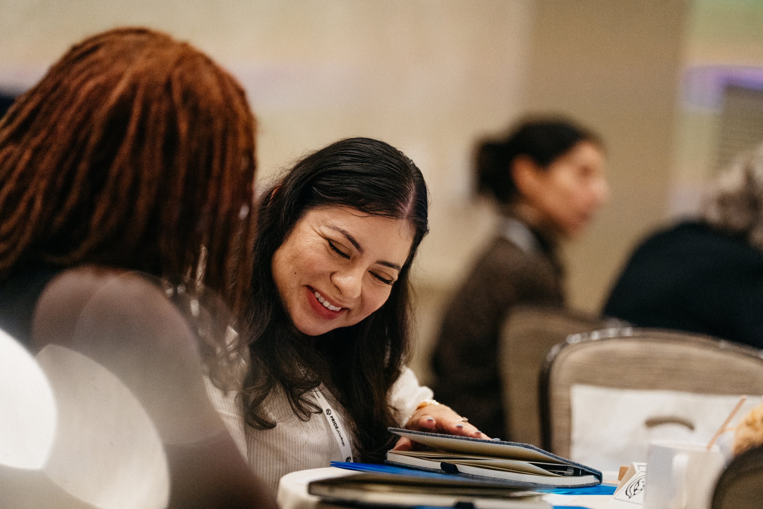 Two women in conversation, smiling, looking at a notebook during a presentation about fundraising
