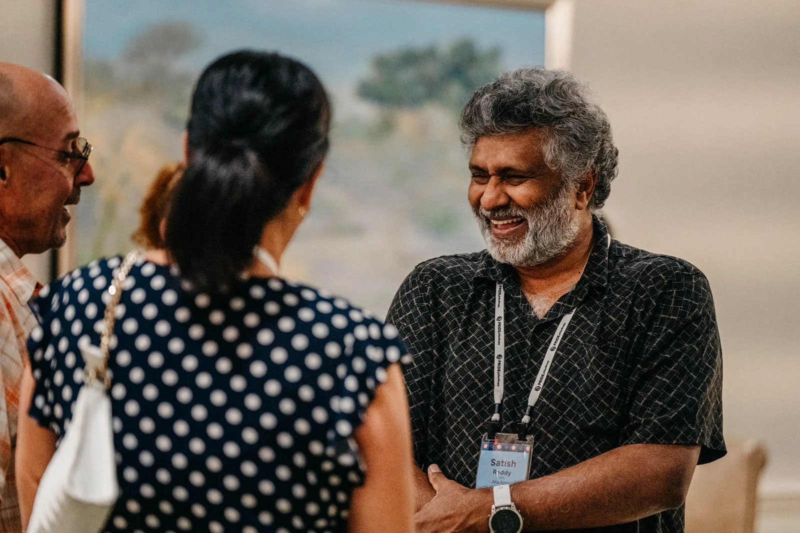 South Asian man smiling, engaged in conversation at a PRIDE Philanthropy educational event about fundraising