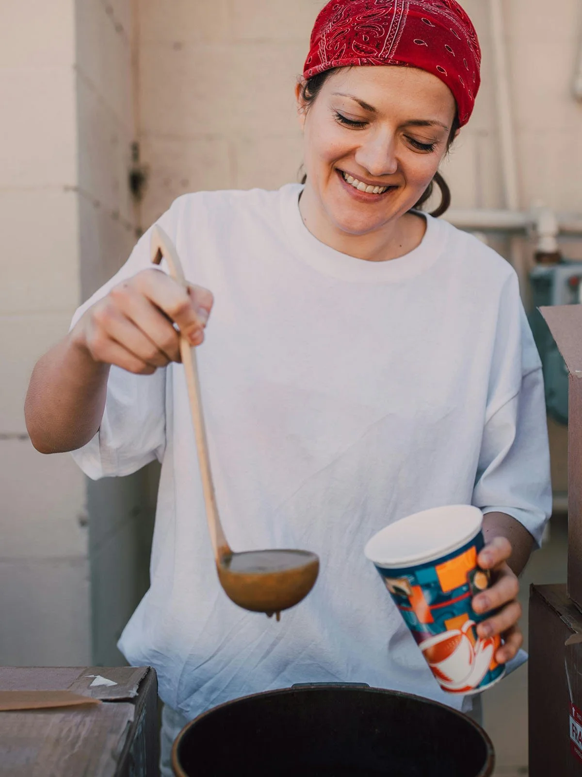 Female volunteer smiling, putting soup in a cup