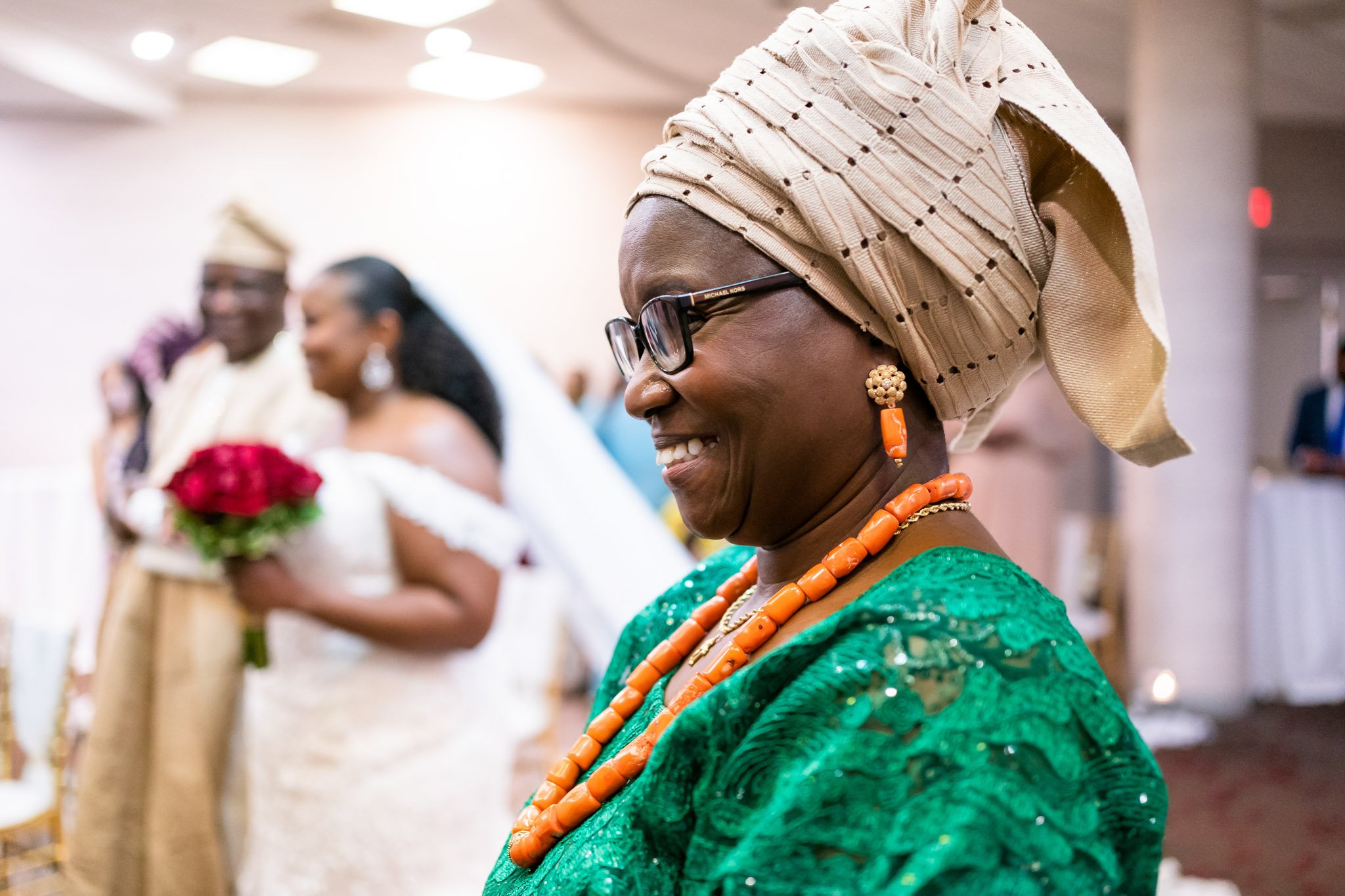 A wedding guests with a head wrap and orange necklace in a green dress in DFW Texas The Amber Studio