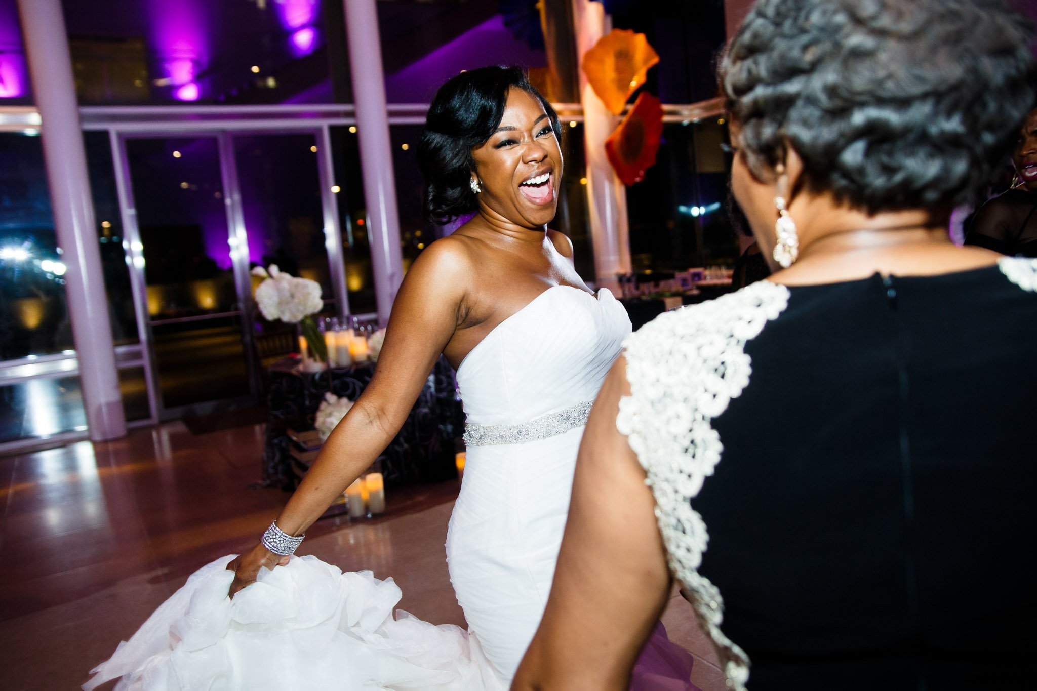 A black bride smiling wide while dancing at the wedding reception in Dallas Texas the Amber Studio