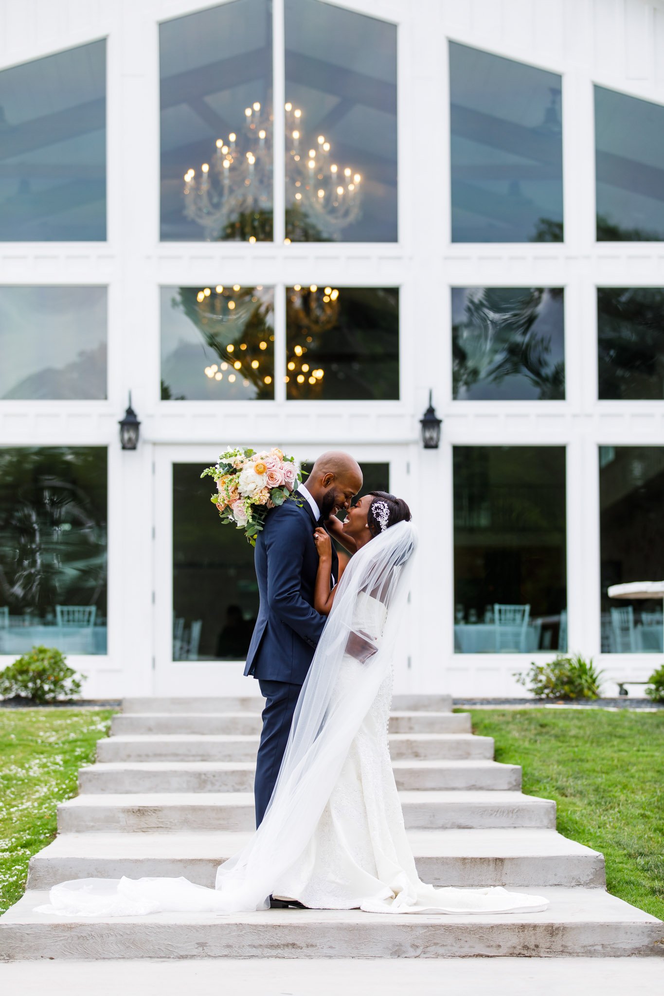 A bride and groom lean in to kiss outside their large wedding reception hall in Dallas The Amber studio