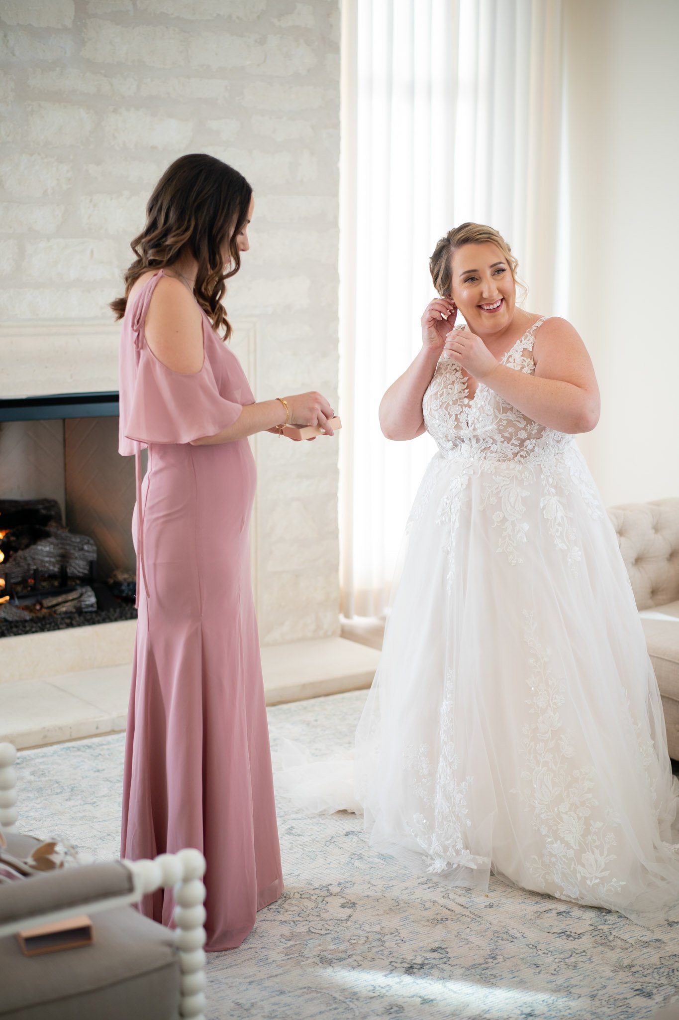 A white bride putting on earrings with help from a bridesmaid at The Arlo in Texas The Amber Studio