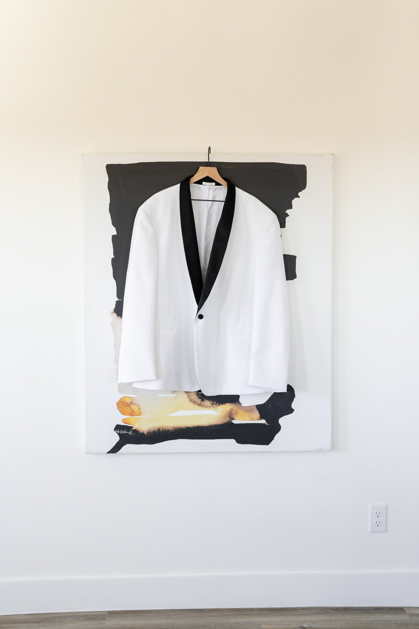 A white suit jacke with a black collar hanging on a painting at The Arlo Austin TX The Amber Studio