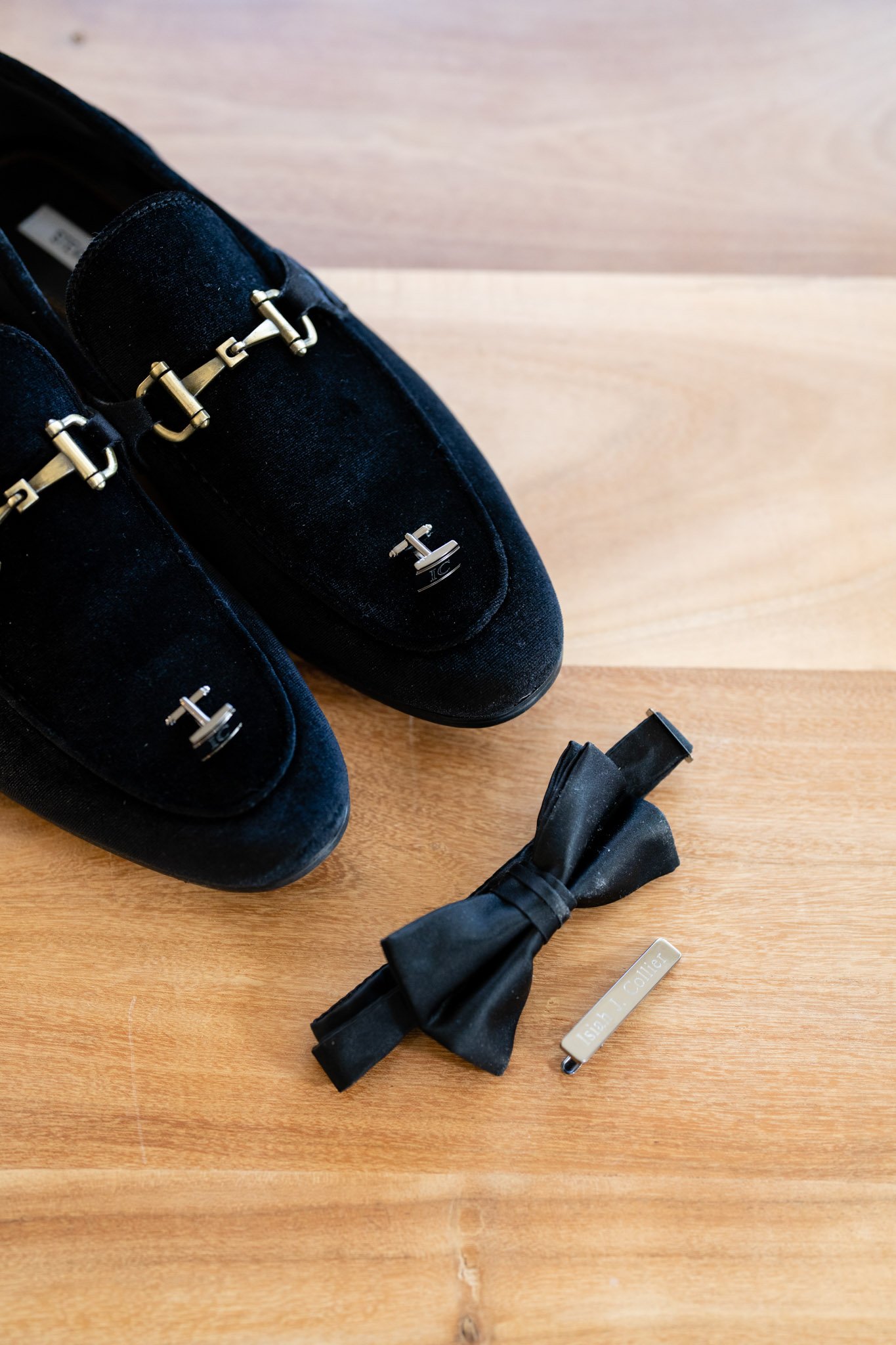 The grooms shoes bowtie cufflinks and tie clip arranged in a row in Austin Texas The Amber Studio