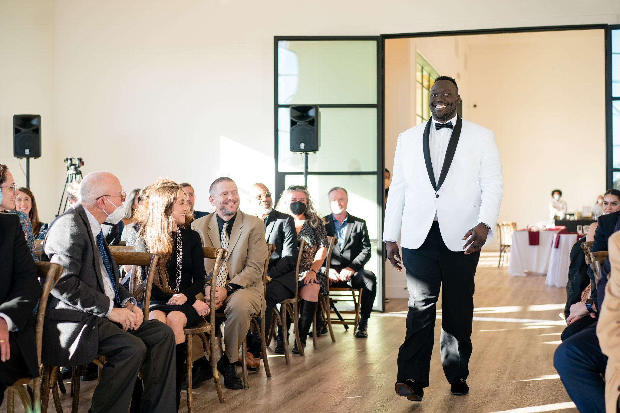 A black groom walking down the aisle before smiling guests at the Arlo Austin TX The Amber Studio