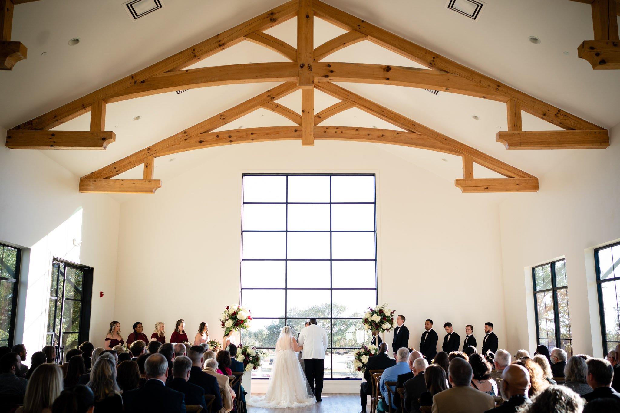 A wedding ceremony in a large room with wooden beams at The Arlo TX The Amber Studio