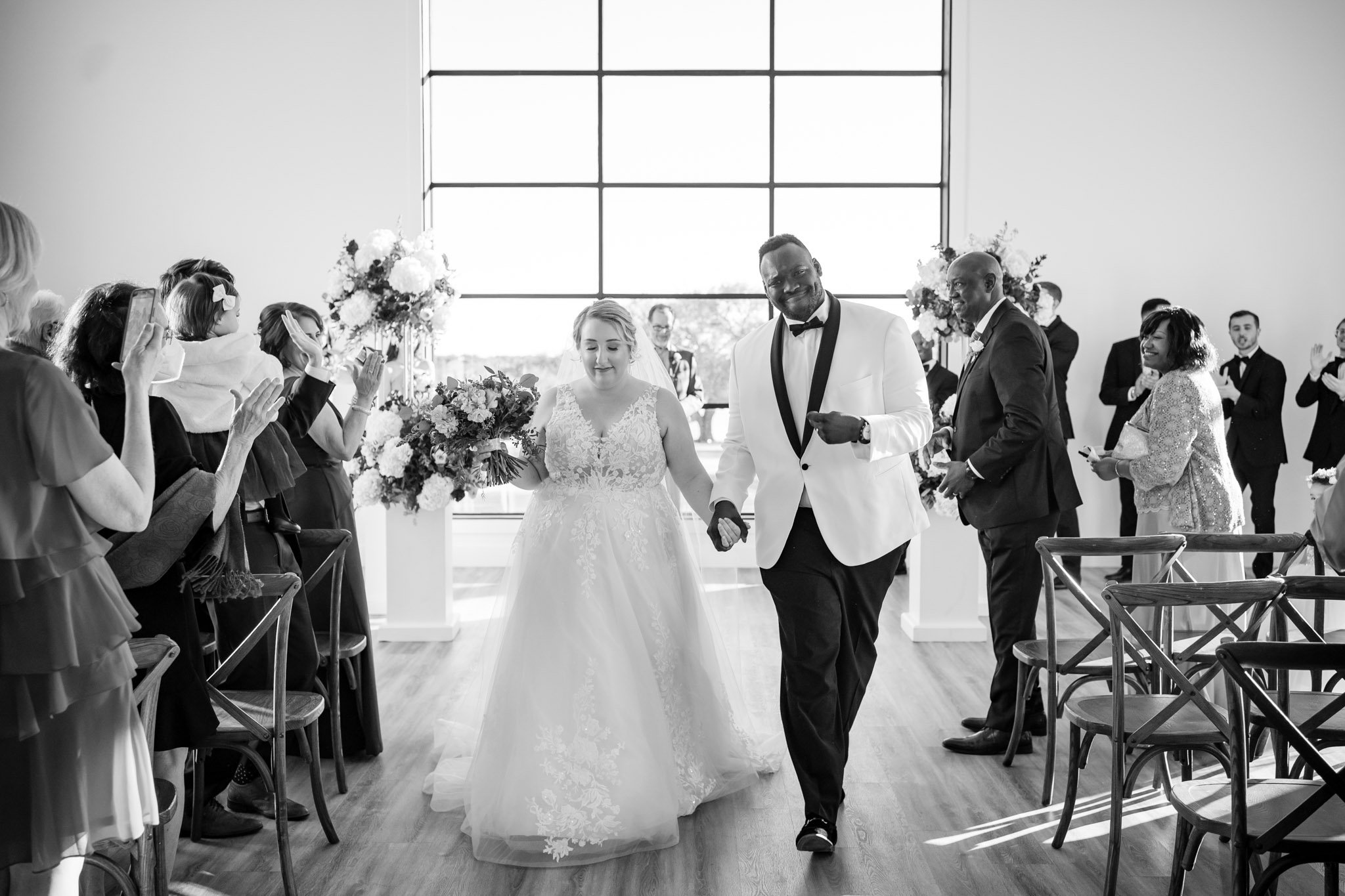 Happy newlyweds walk back up the aisle as guests applaud at The Arlo Texas The Amber Studio