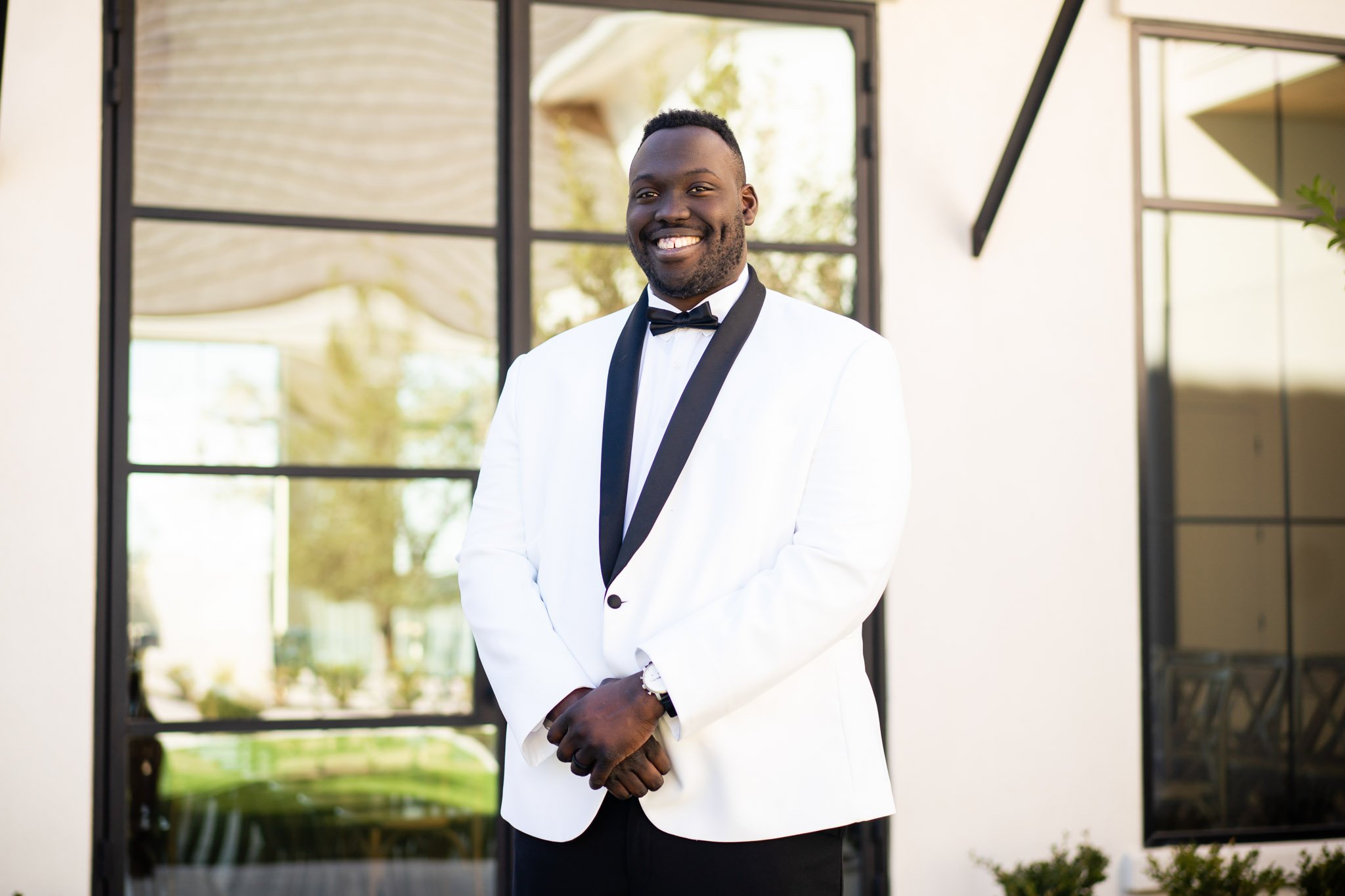 A black groom smiling in a white suit jacket with a bowtie at The Arlo in Austin TX The Amber Studio