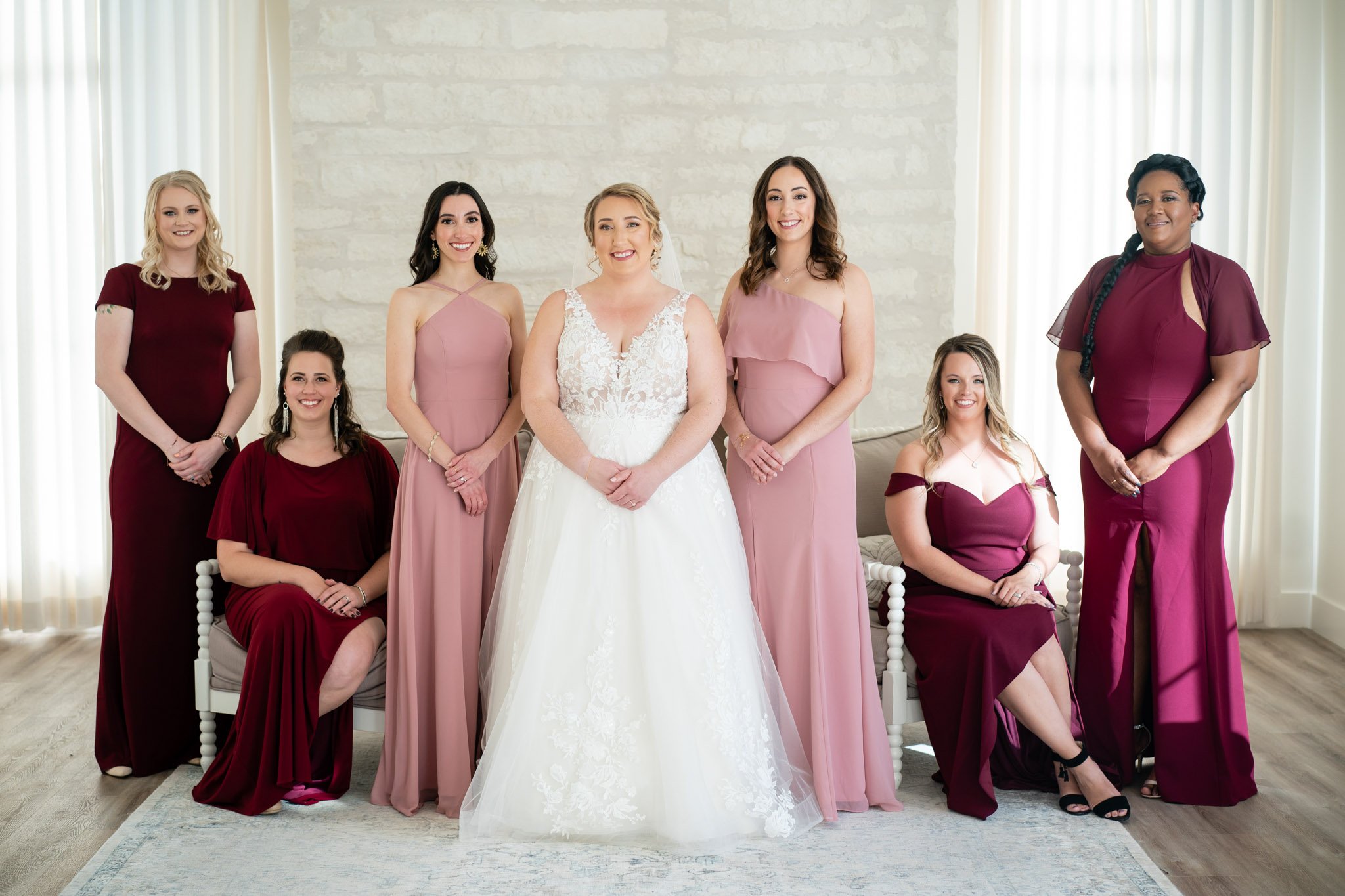 Bride smiling with bridesmaids in pink and burgundy dresses at The Arlo in Austin The Amber Studio